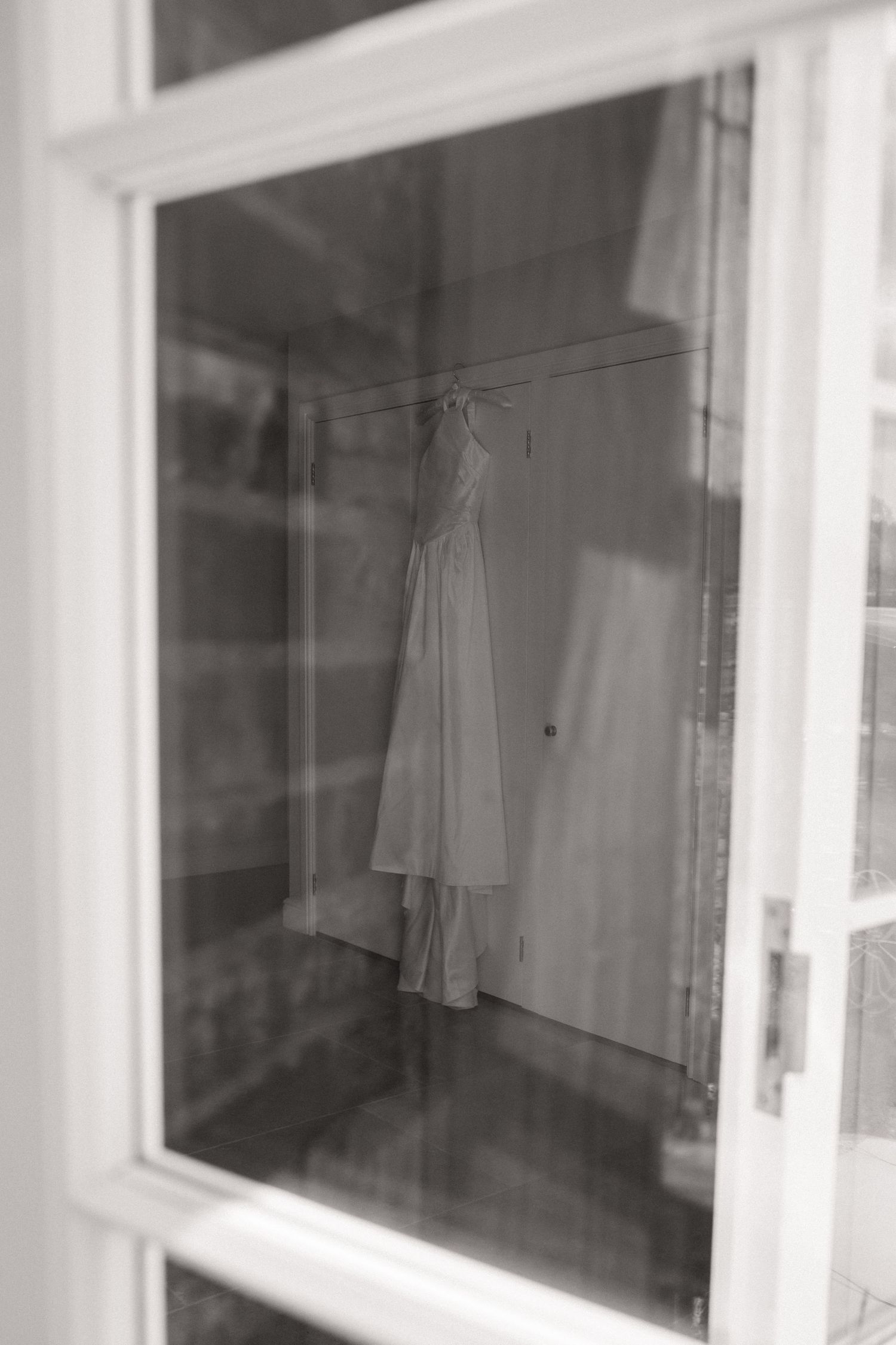 White lab coats hanging on hooks against a white wall in a medical or laboratory setting.