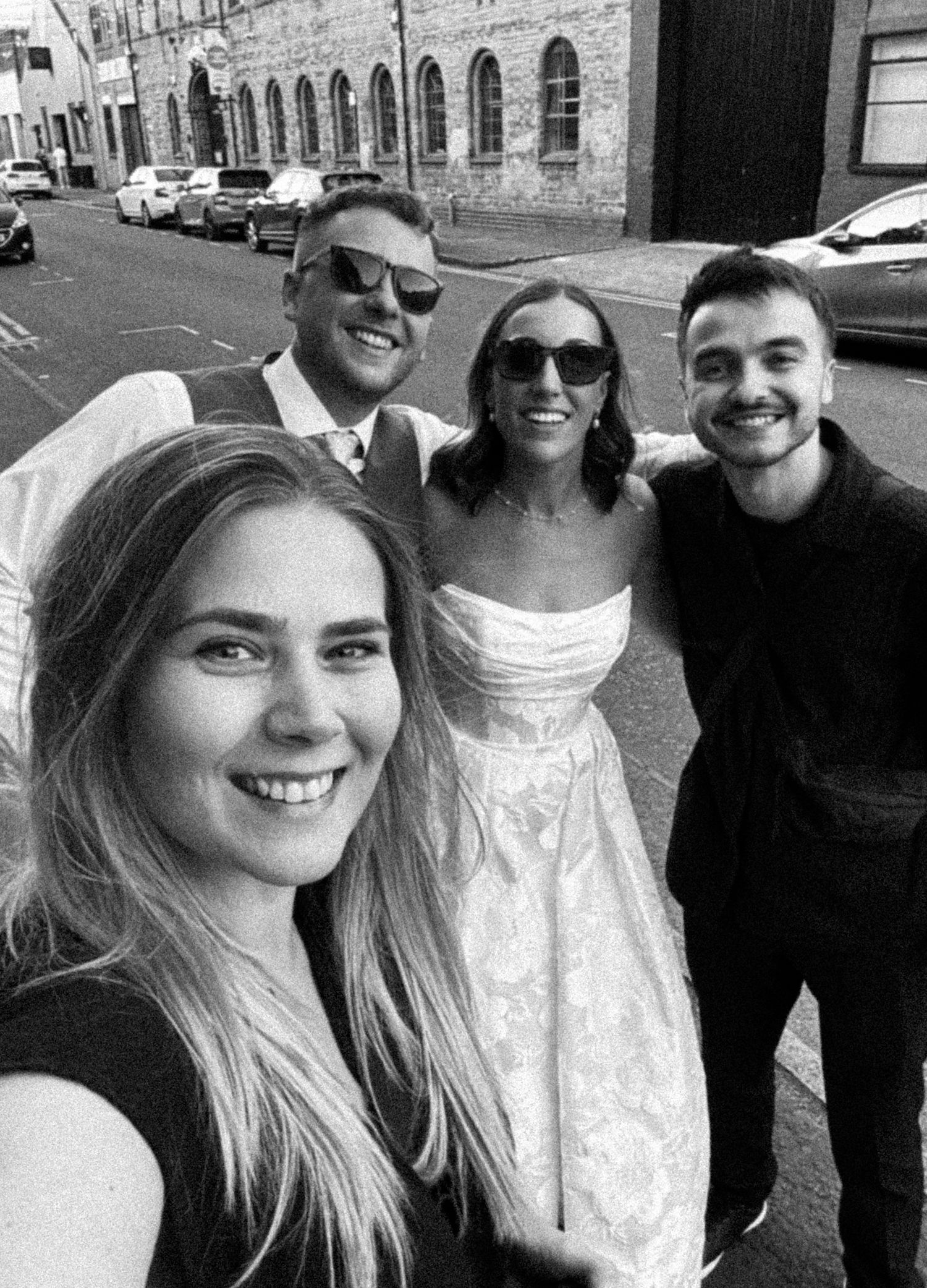A series of four black and white selfie photos showing people smiling and posing together outdoors.