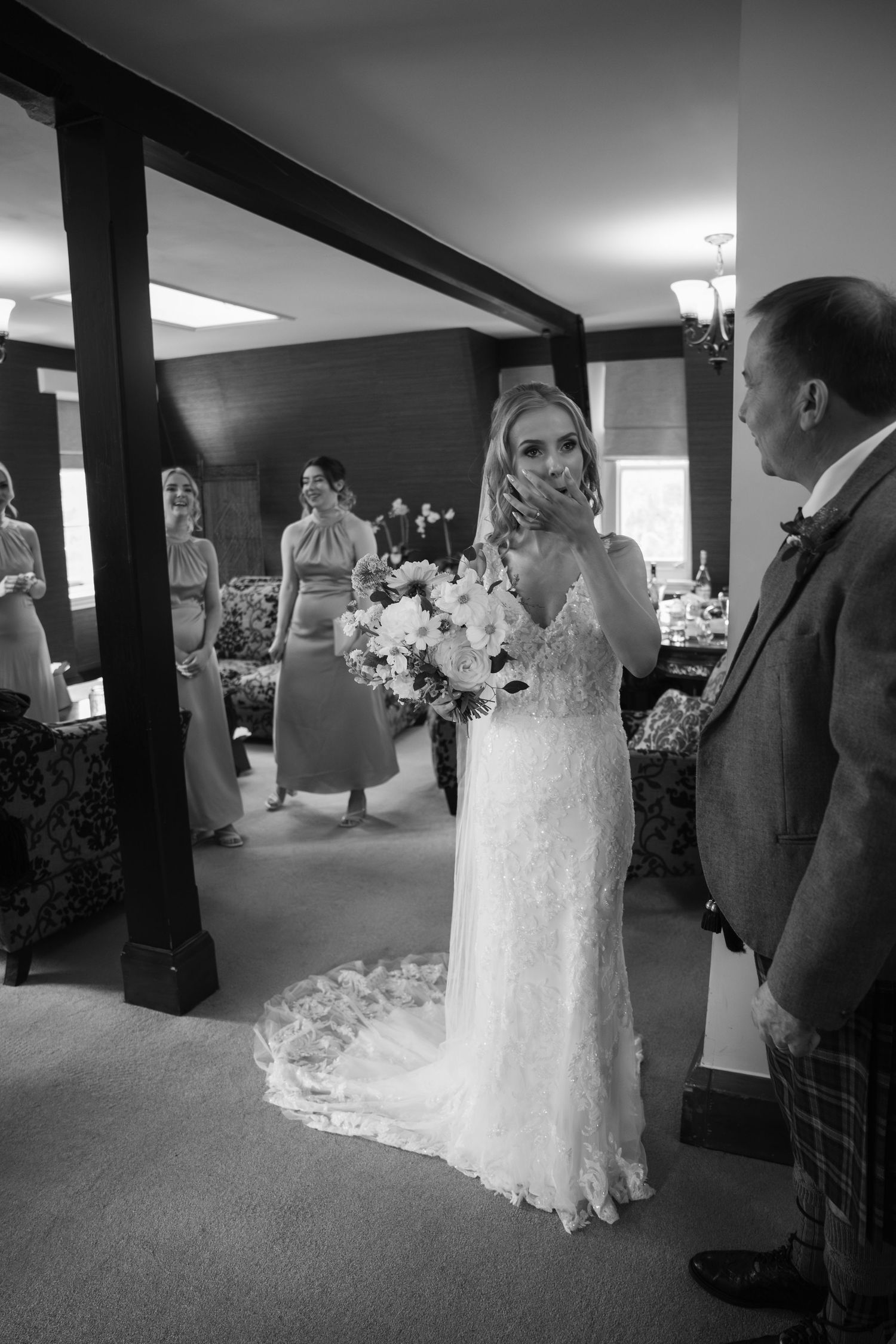An elegant wedding scene in black and white showing a bride in a lace gown with a bouquet.
