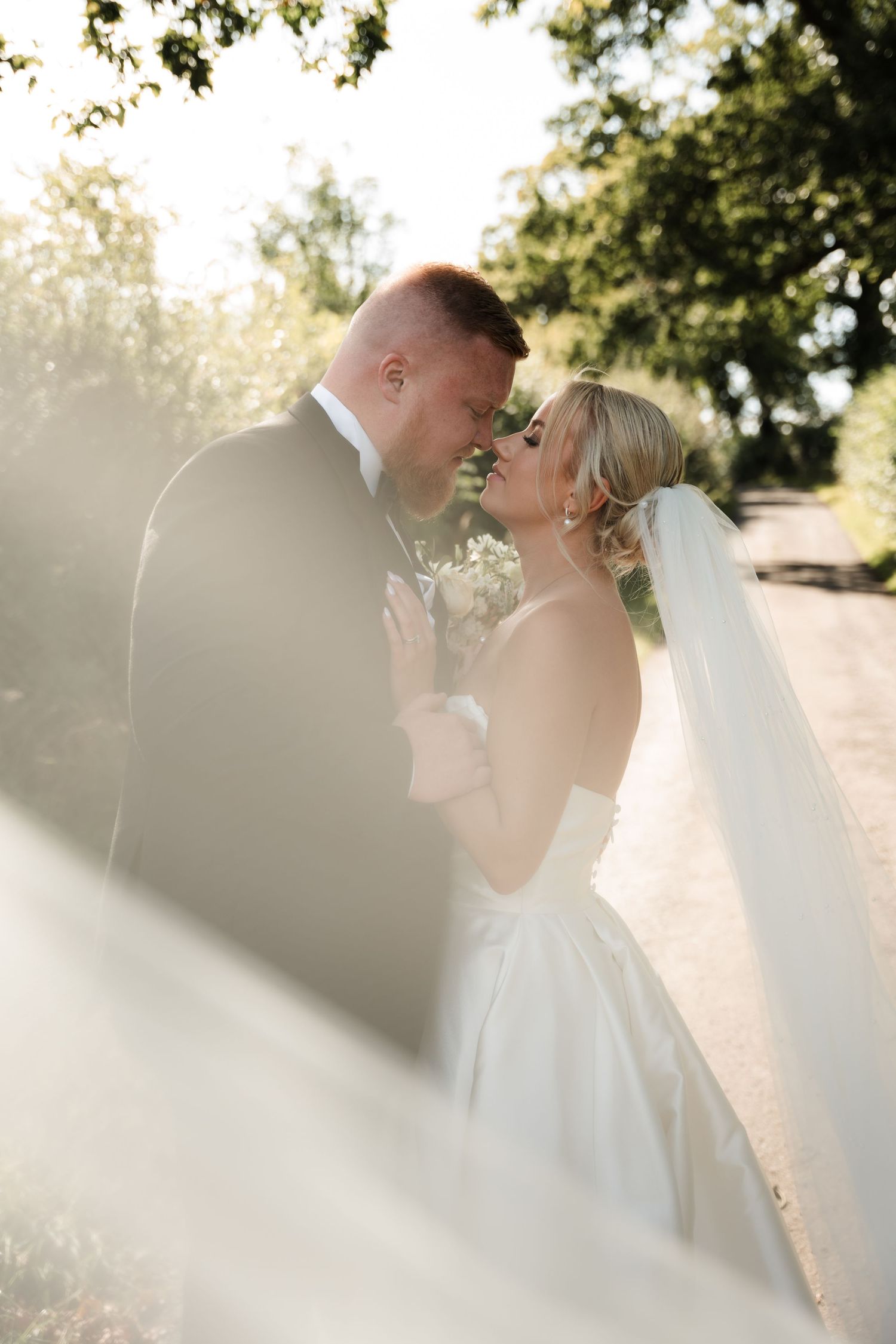 A romantic outdoor wedding sequence shows a couple sharing tender kisses under sunlit trees in matching white attire.