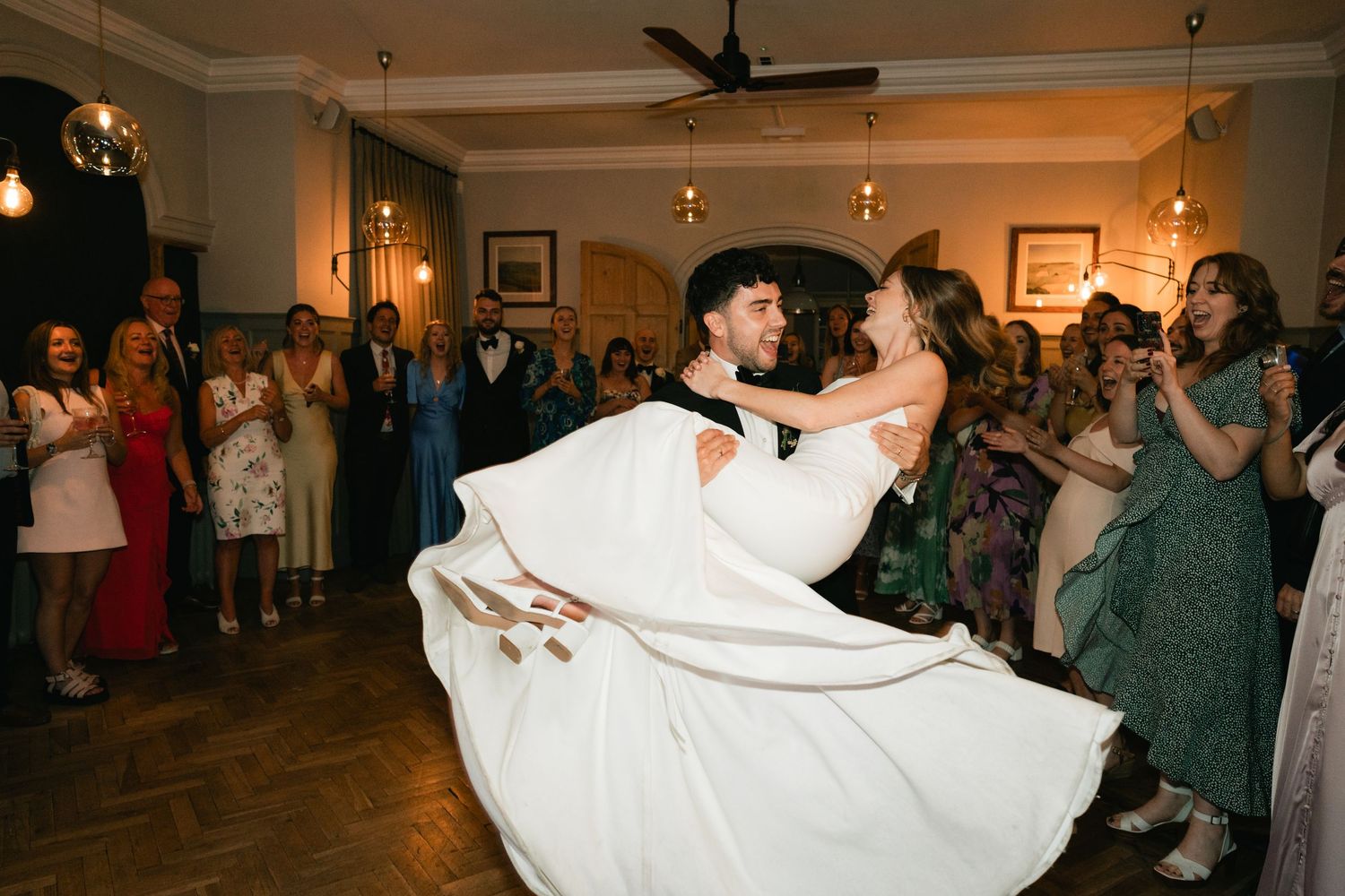 A couple shares a romantic dance dip during a dimly lit wedding reception celebration.