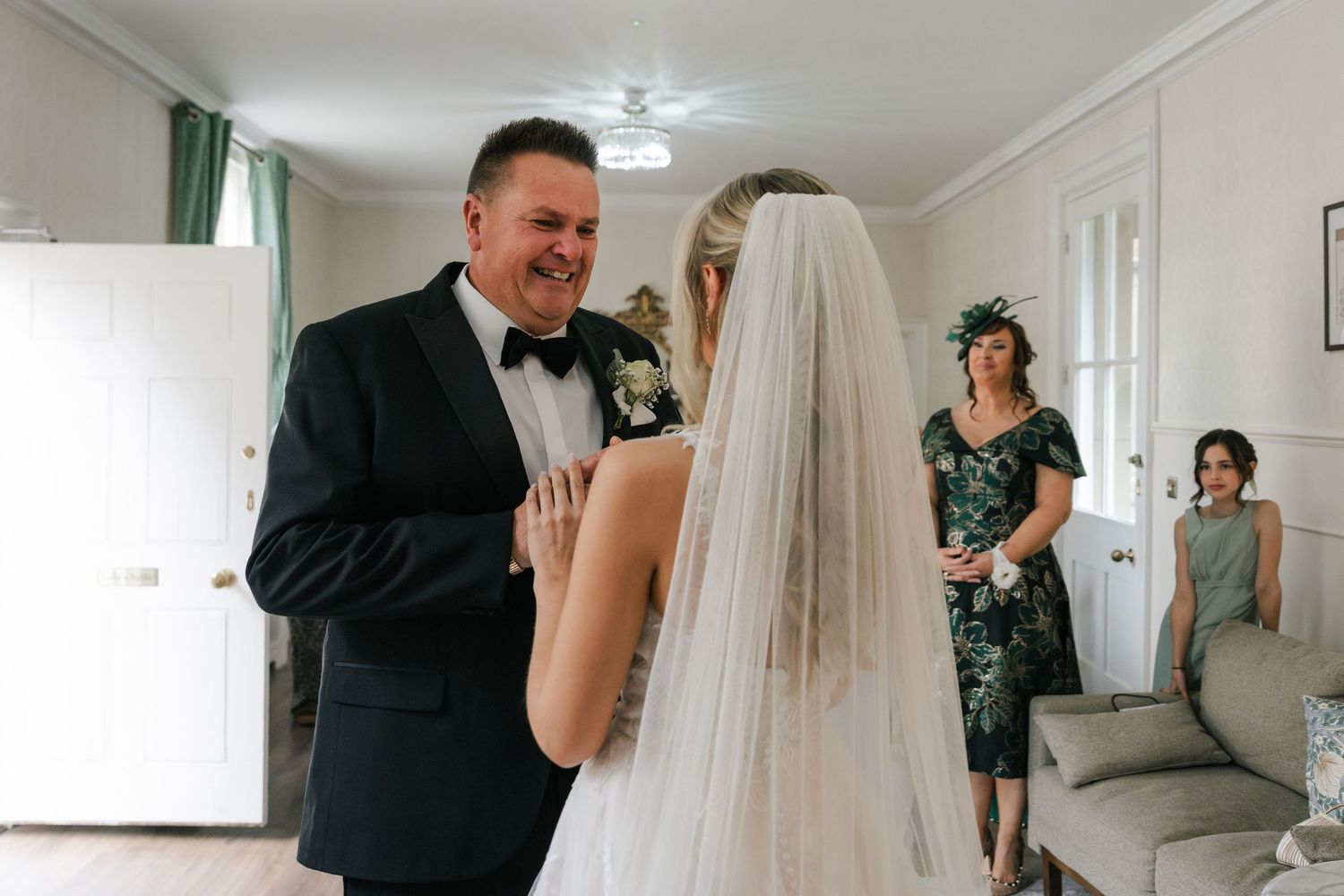 A wedding party shares joyful moments and embraces during preparations in a bright indoor setting.