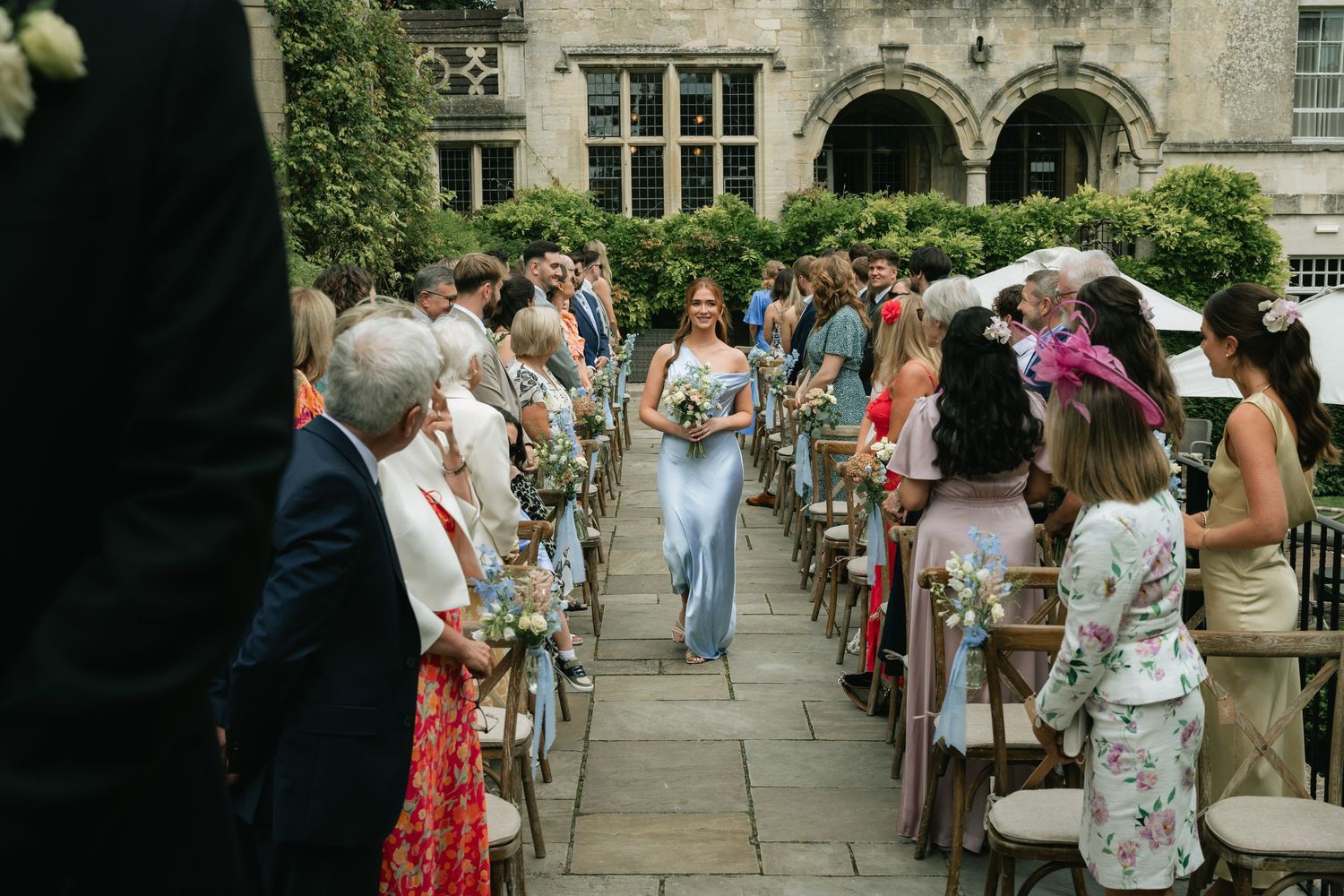 Wedding guests stand in line on a stone patio during an outdoor reception gathering.