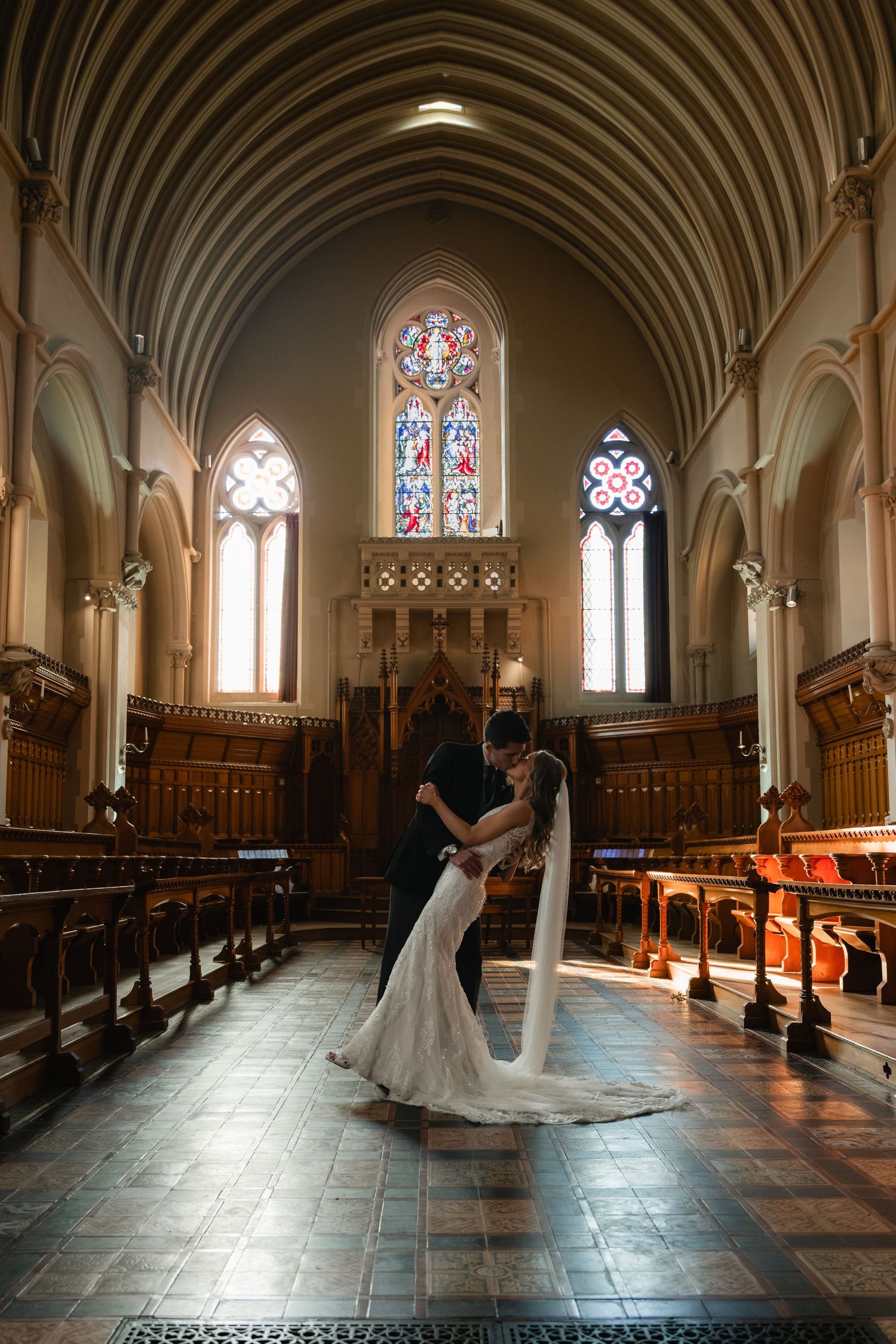 Elegant cathedral interior with vaulted ceilings, stained glass windows, and wooden pews bathed in natural light.