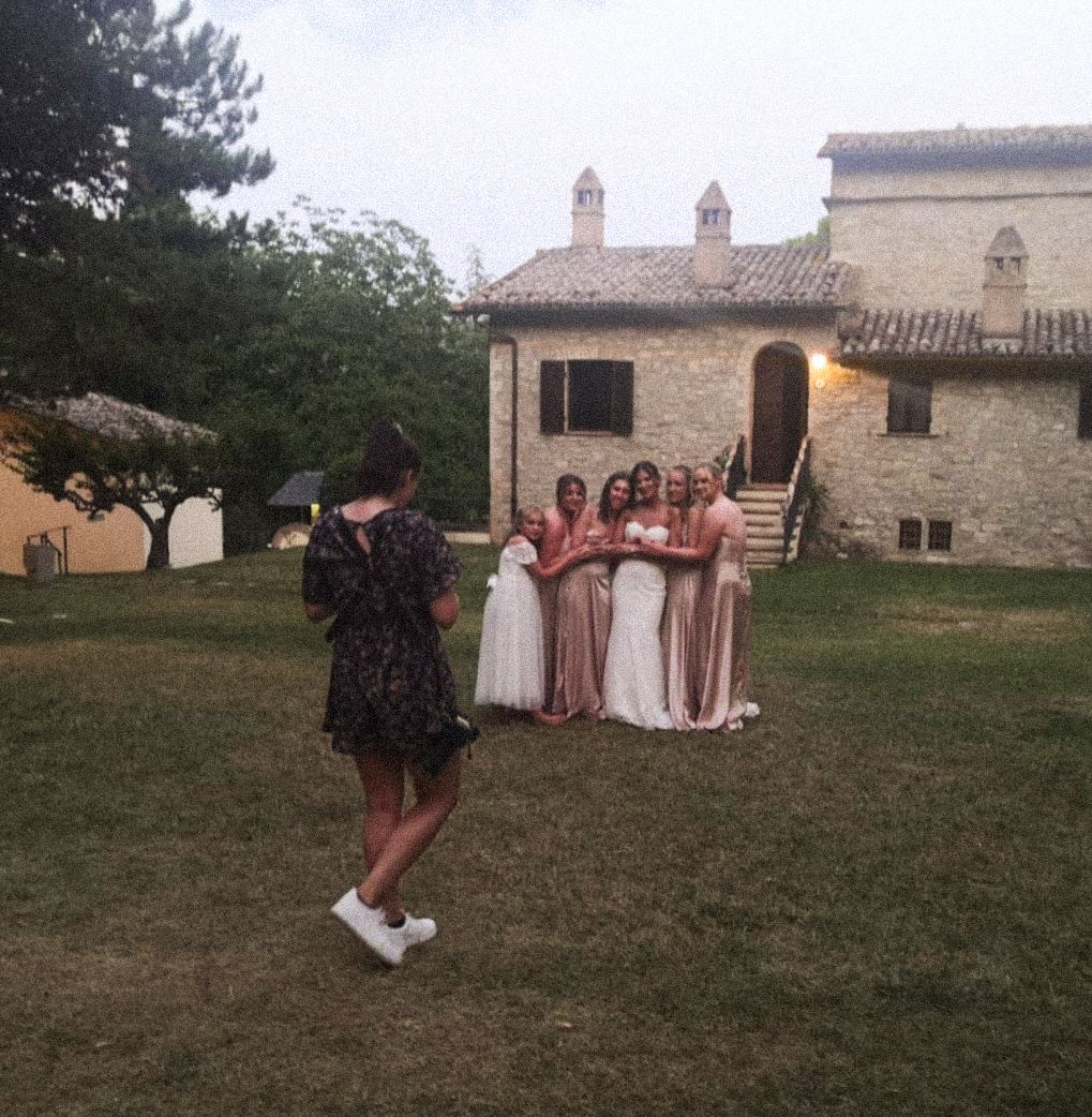 A photographer captures a group photo outside a rustic Italian villa.