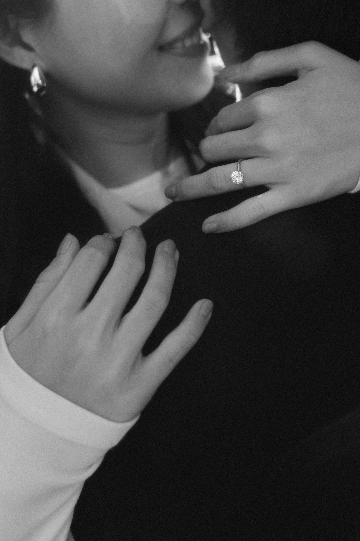 Artistic black and white close-up of hands tenderly touching face.