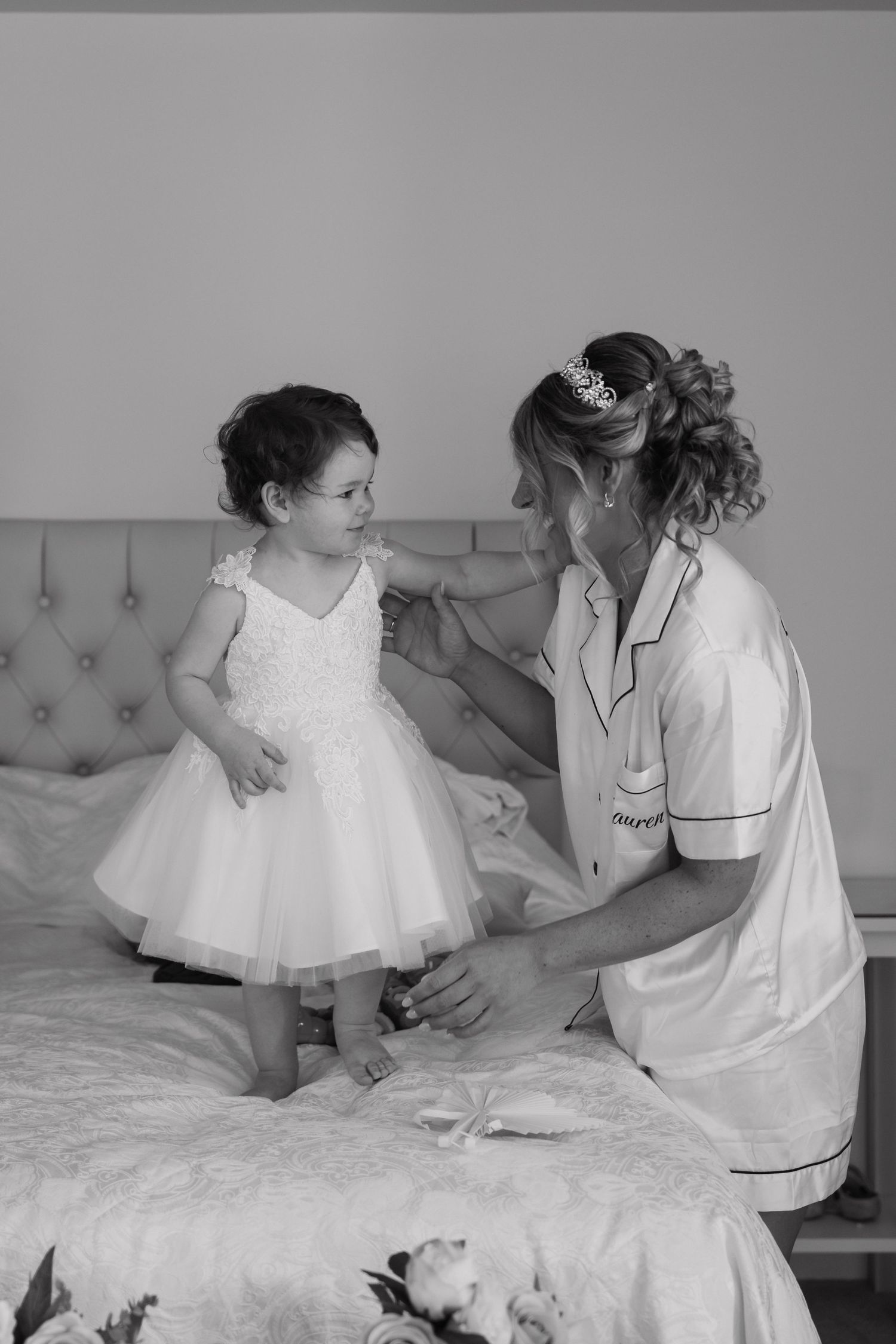 A series of black and white photos showing tender moments between two people sitting on a bed in white clothing.