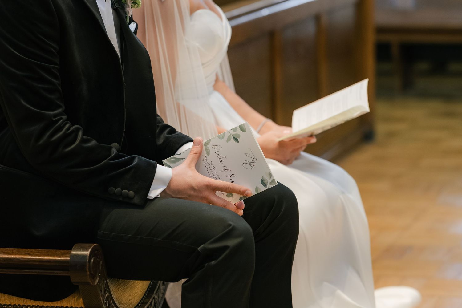 Couple reading from a book during an intimate wedding ceremony in a church setting.
