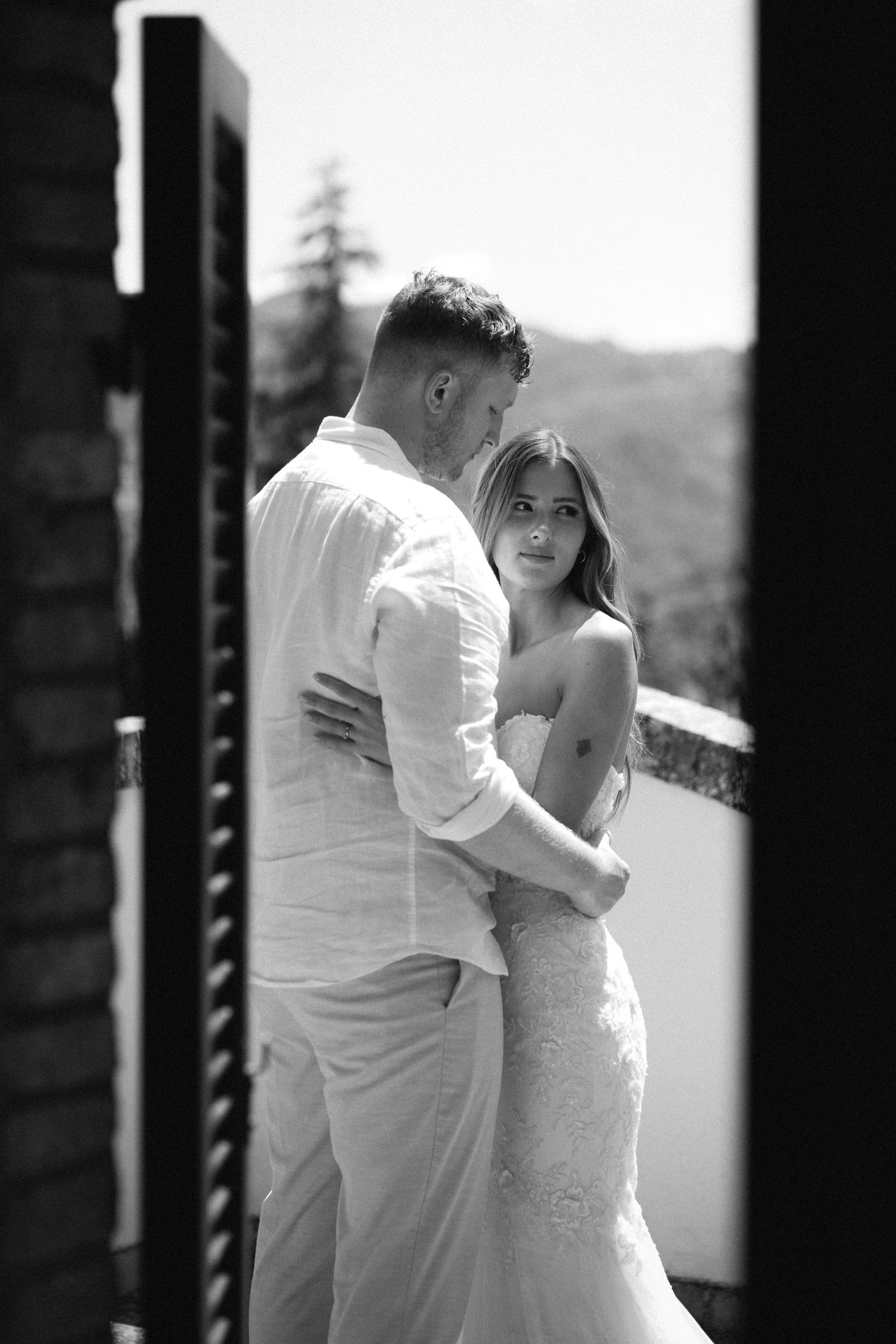 A romantic black and white photo series showing a couple in white embracing during an intimate wedding moment.
