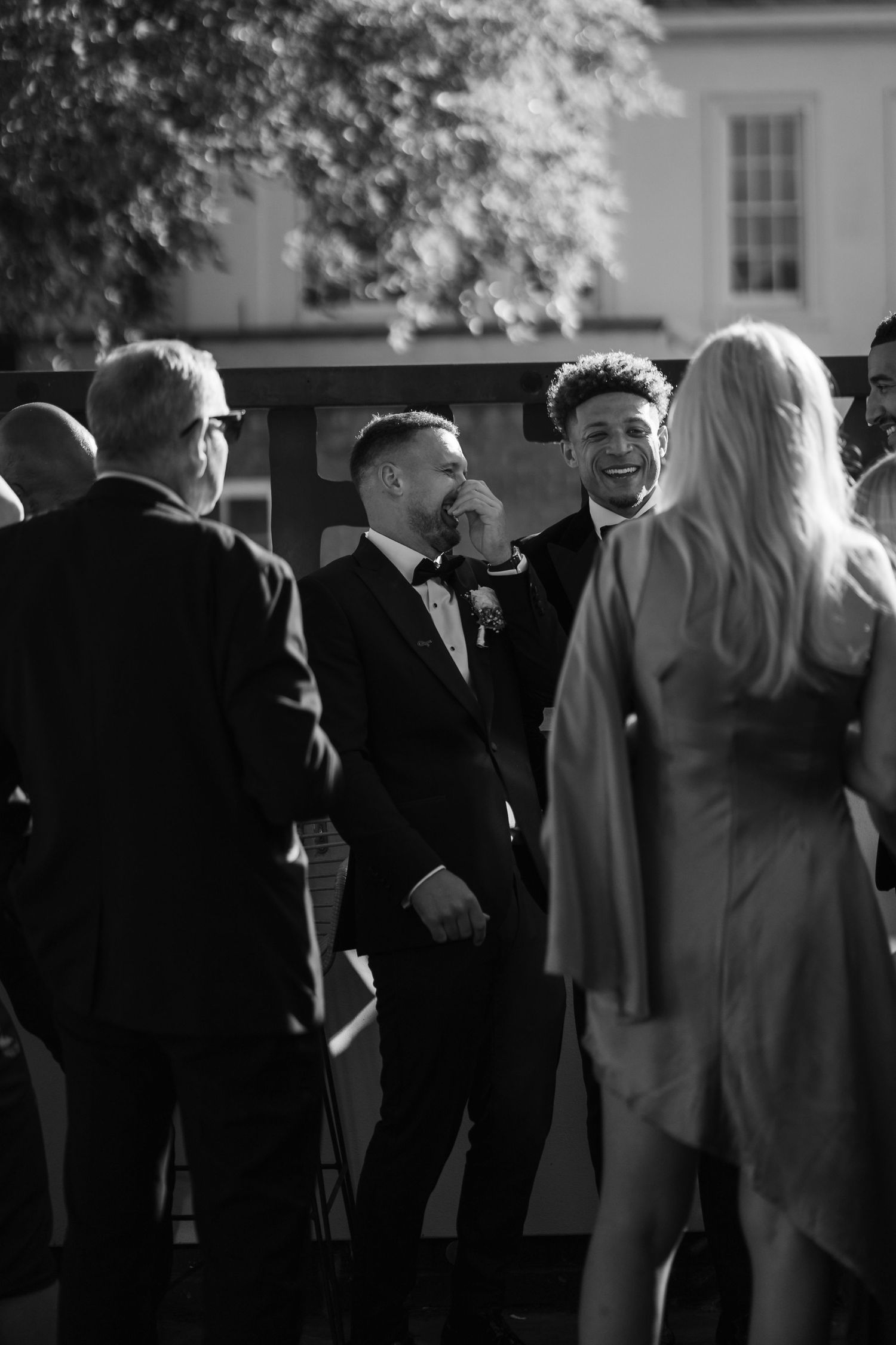 A black and white photo sequence shows a group of people in formal attire mingling at an outdoor social gathering.