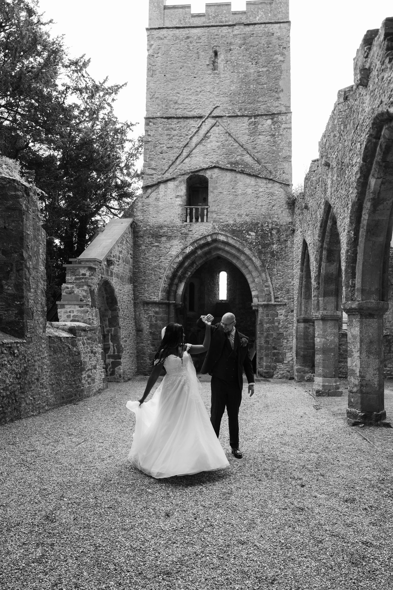 A sequence of black and white photos showing a couple walking through the stone archways of a historic church exterior.