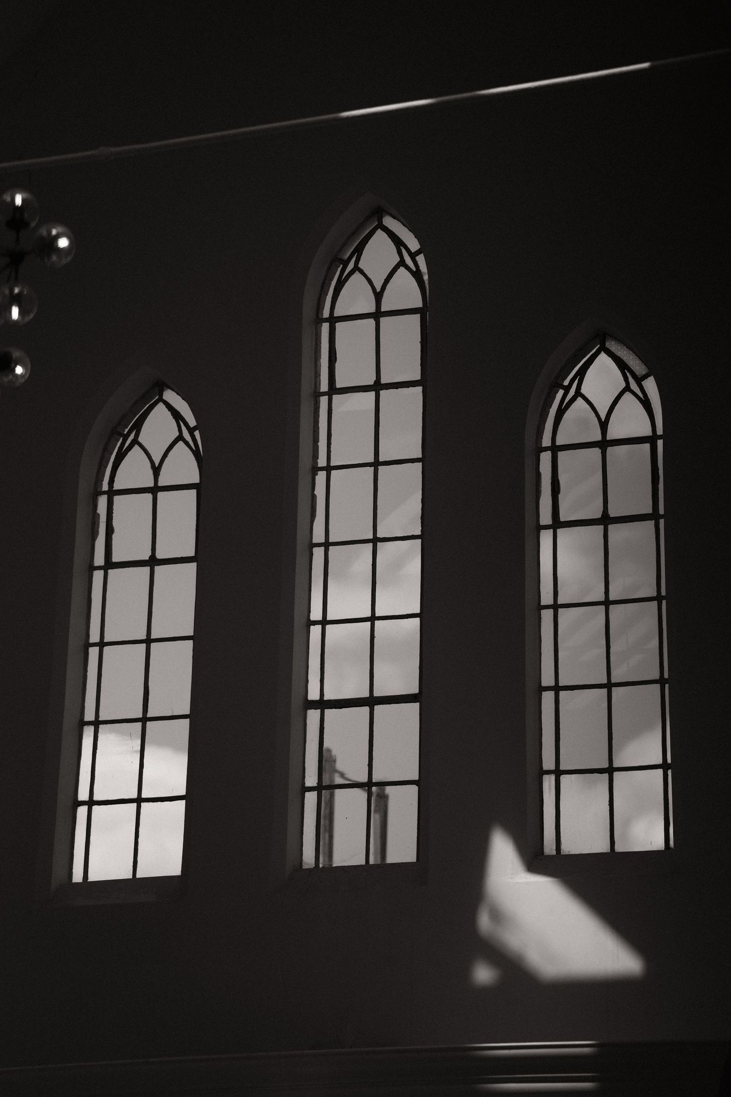 A series of Gothic church windows in a dark room creating a dramatic silhouette effect.