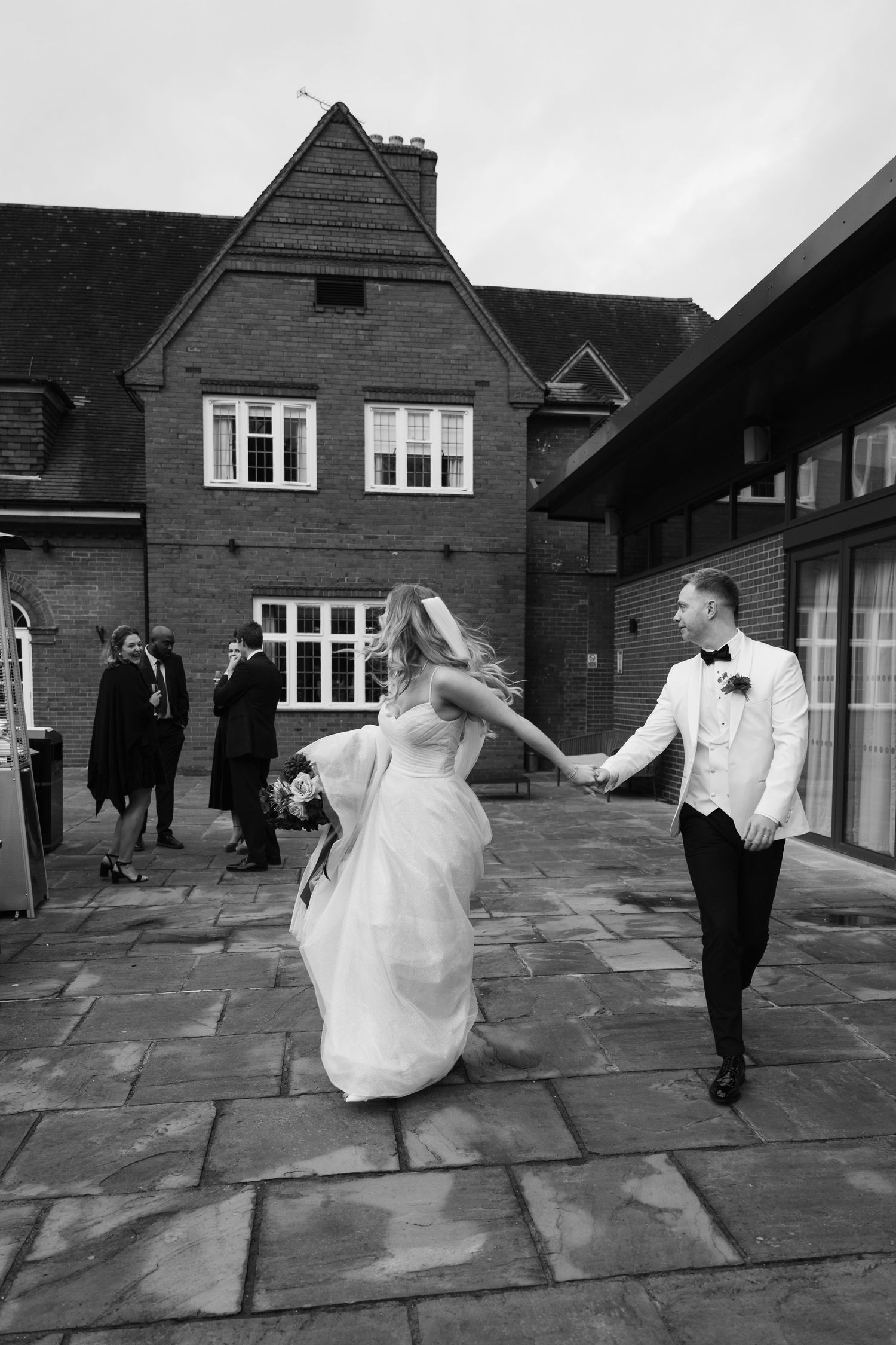 Black and white sequence of a bride twirling in her wedding dress on a stone patio.