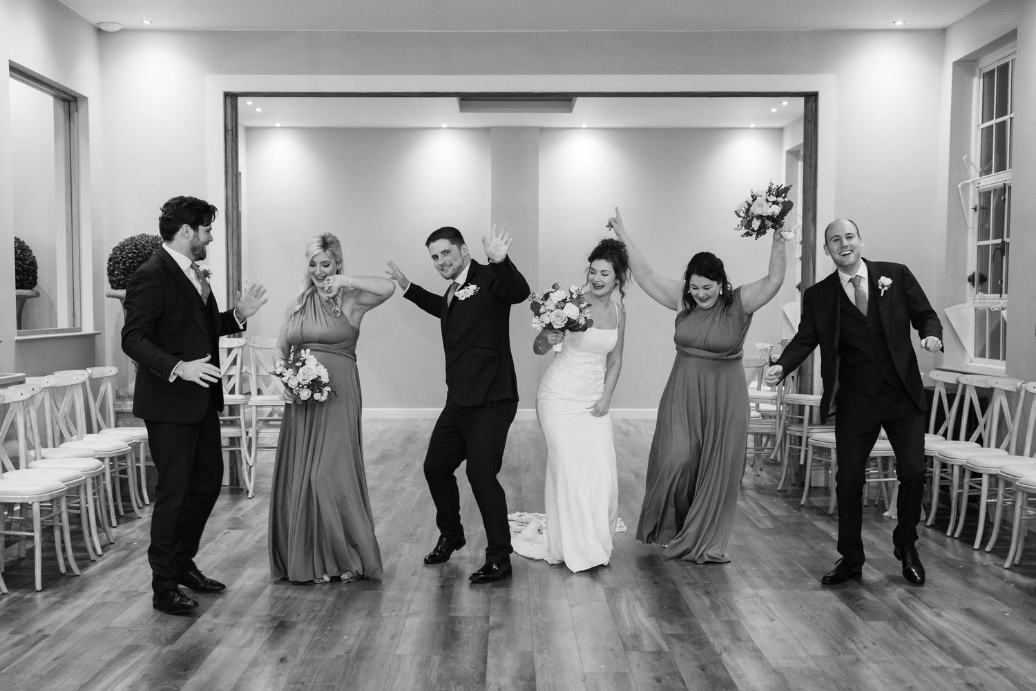 A black and white panoramic sequence shows a wedding party dancing and celebrating in an elegant indoor venue.