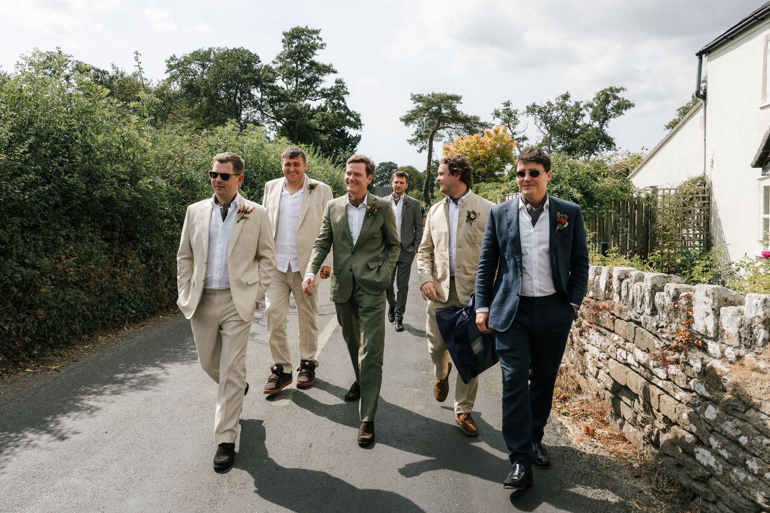 A group of people walking down a stone path in light colored formal attire.