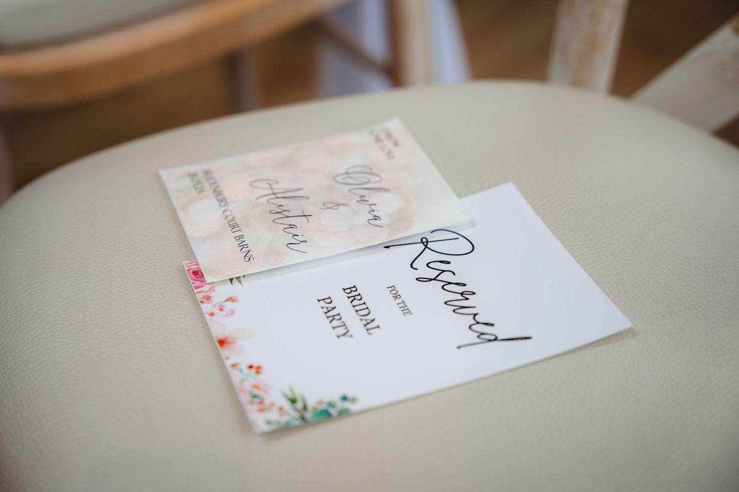 A collection of white paper cards or envelopes with floral designs arranged in a row on a wooden surface.
