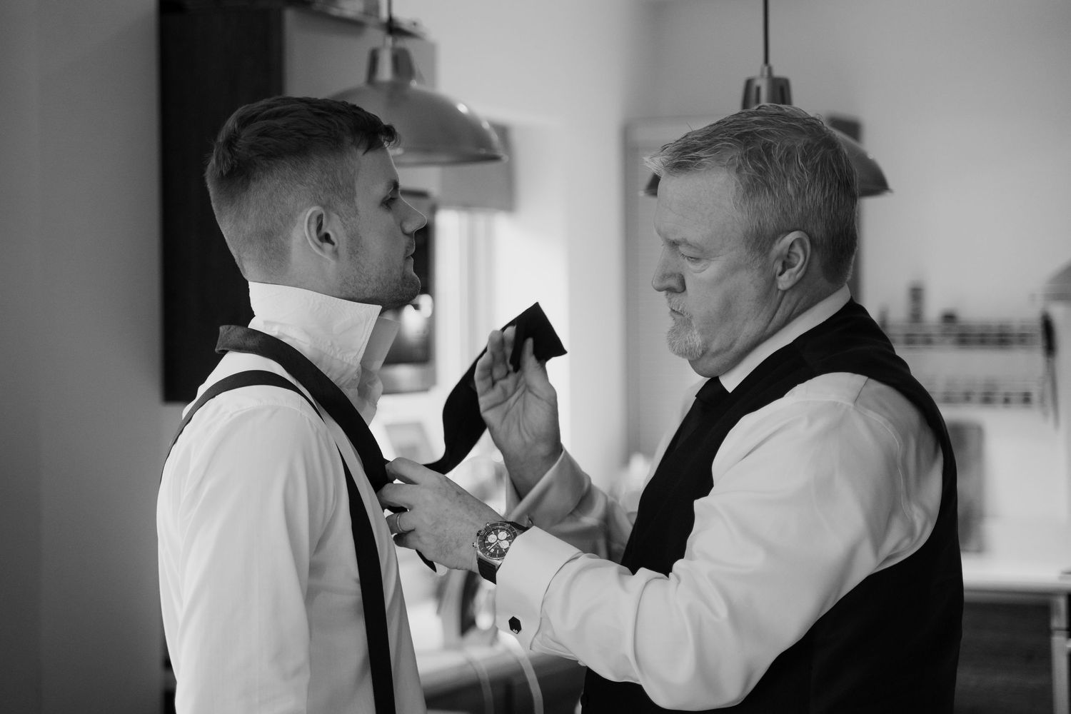 A series of black and white photos showing a father and son sharing emotional moments while getting ready for a wedding.