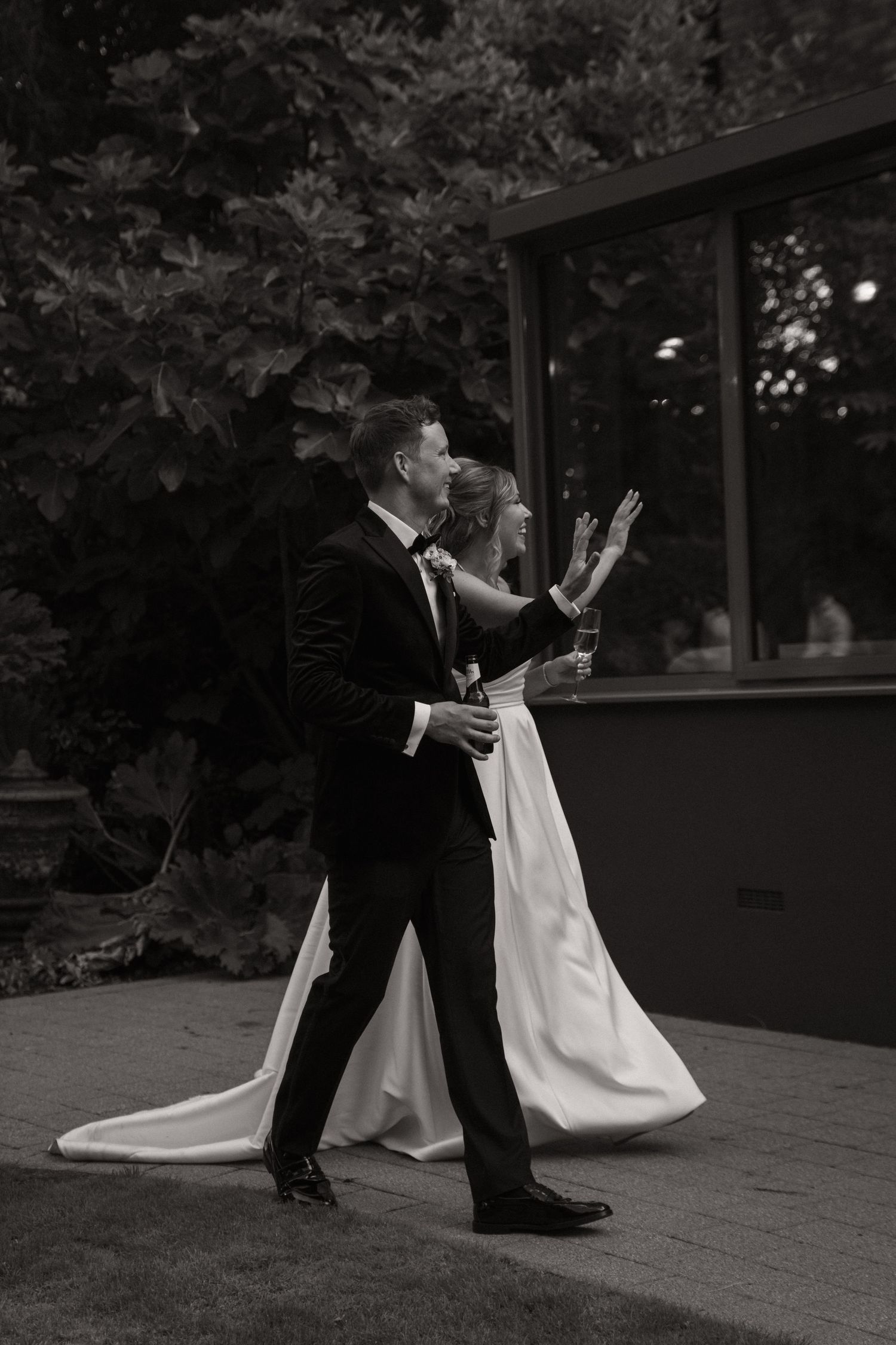 A couple in wedding attire performs a dramatic dance pose together on an outdoor patio at dusk.