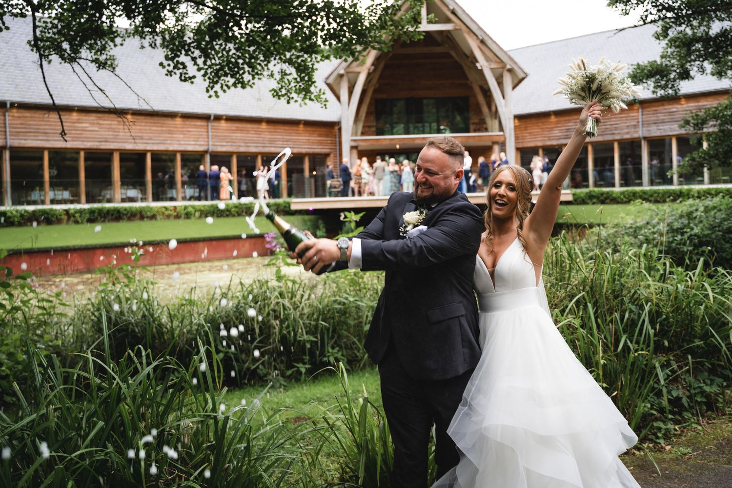 A couple in formal wedding attire shares a romantic dance together in a scenic outdoor garden setting.