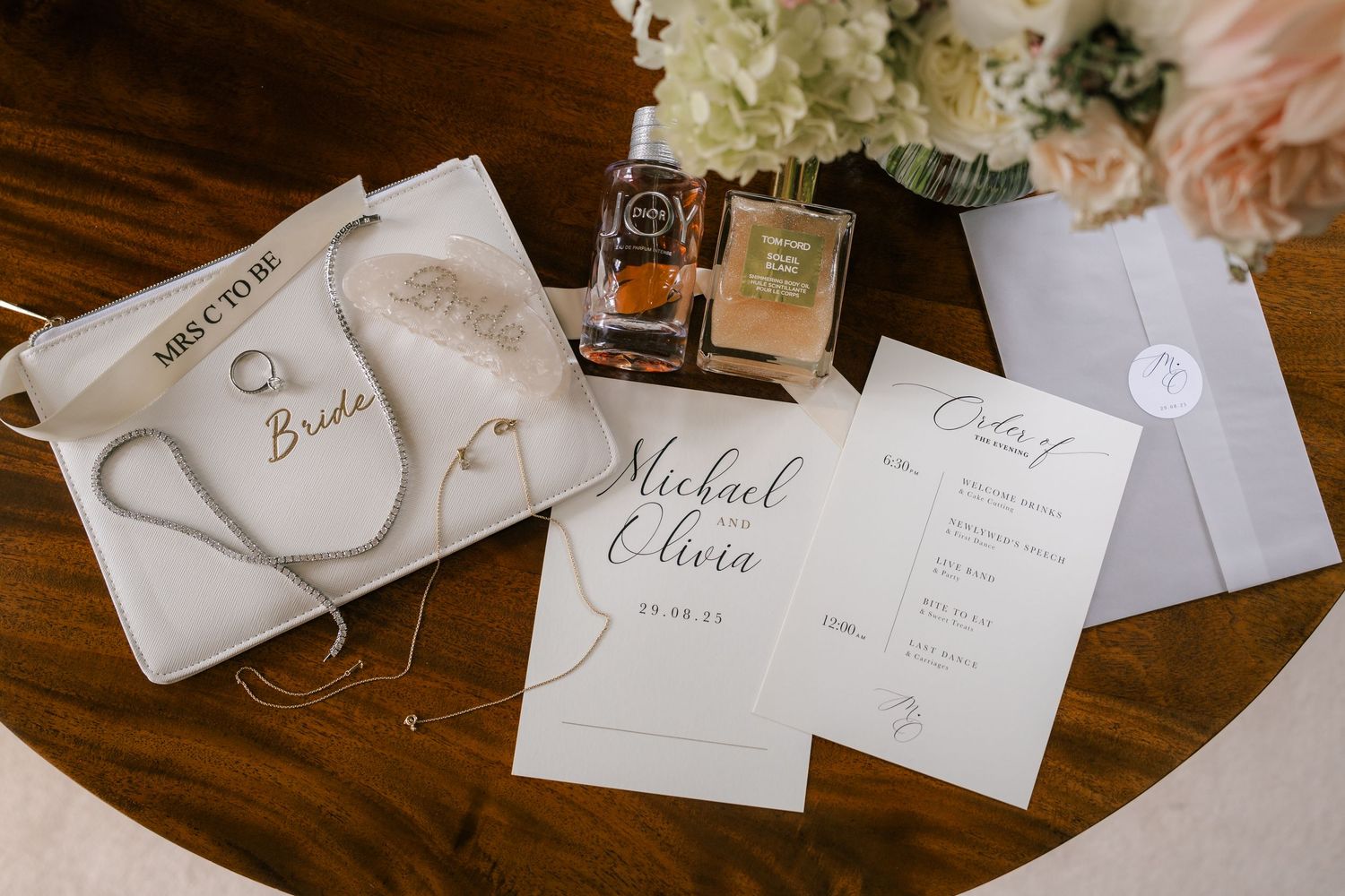 Elegant wedding place cards and name tags with calligraphy displayed on a dark wooden surface.