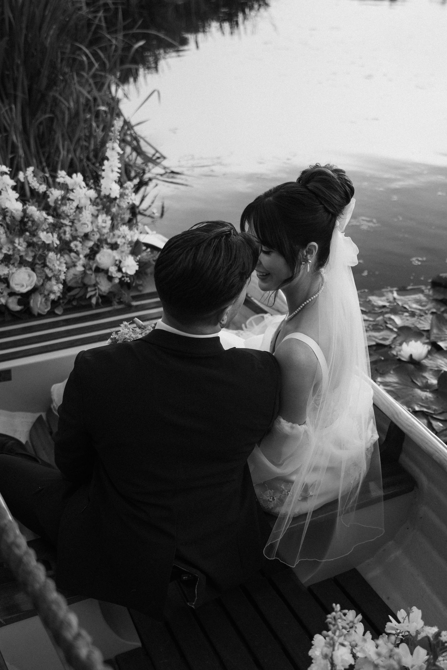 Black and white wedding photo with floral arrangements framing an intimate moment.