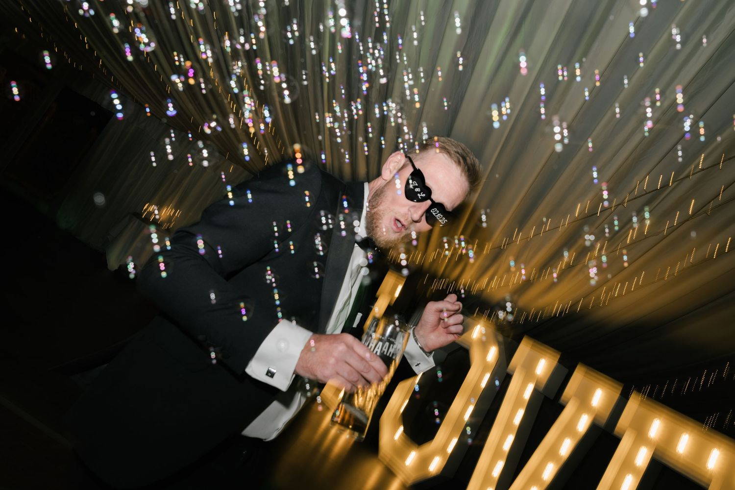 Hanging glass bottles with LED lights create a magical ceiling display at an event venue.