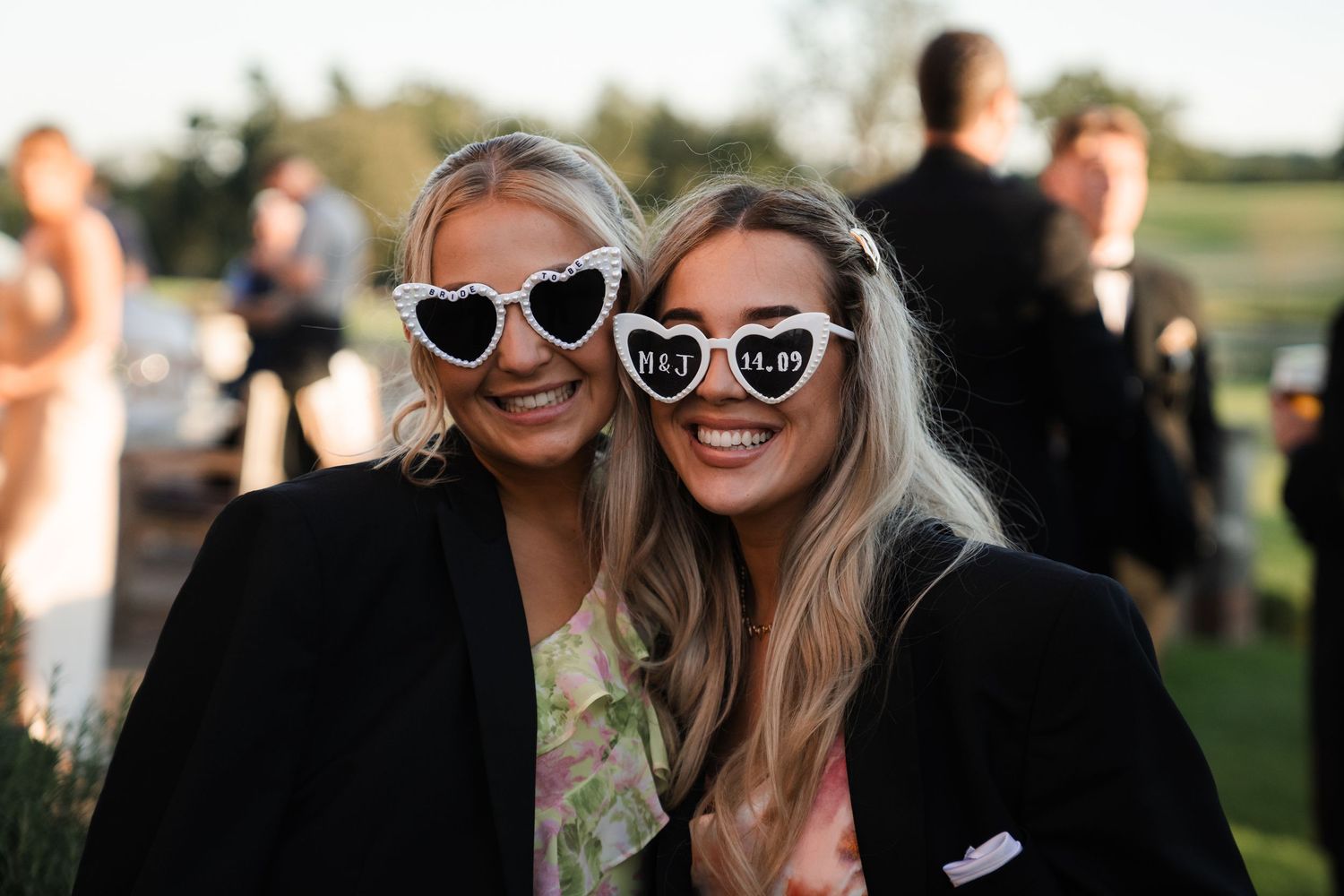 Group of people wearing sunglasses and smiling outdoors at a sunny event.