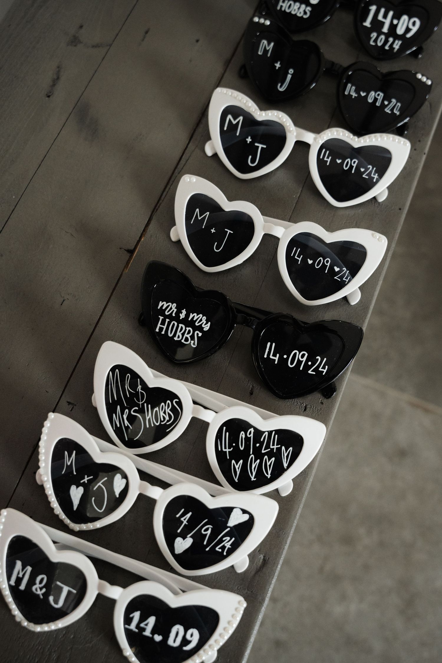 Black and white photo of heart-shaped sunglasses with handwritten numbers arranged in rows on a concrete surface.