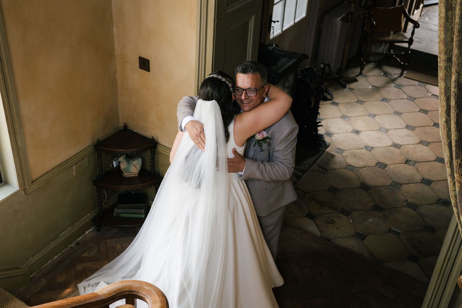 A romantic wedding moment captured on a tiled patio with a flowing white bridal gown and elegant formal attire.