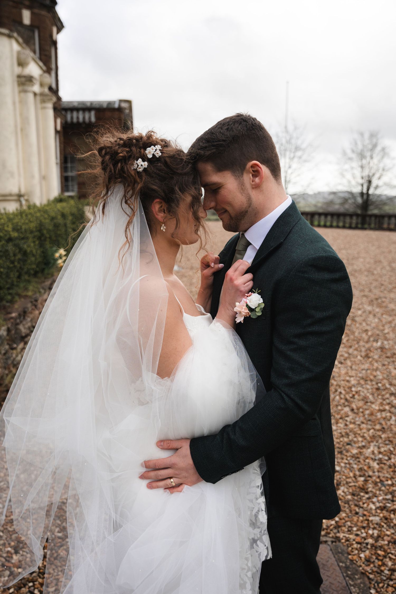 Romantic wedding moment captured against a historic stone building backdrop.