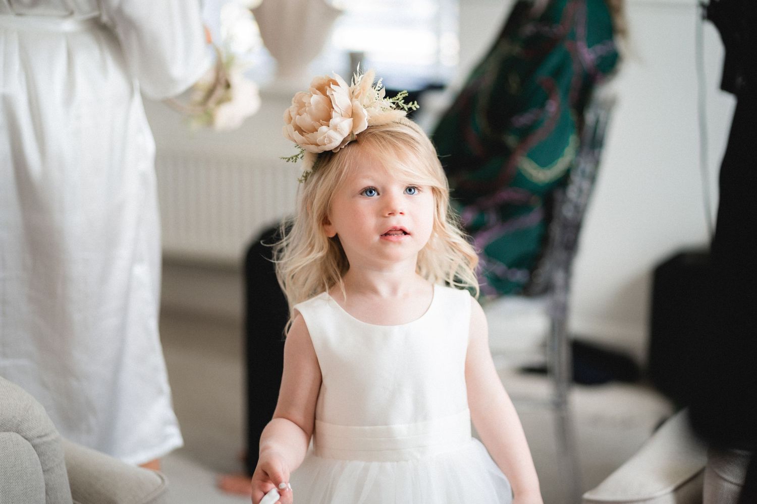A small child in a white dress twirls and dances in a room with turquoise accents on the wall.