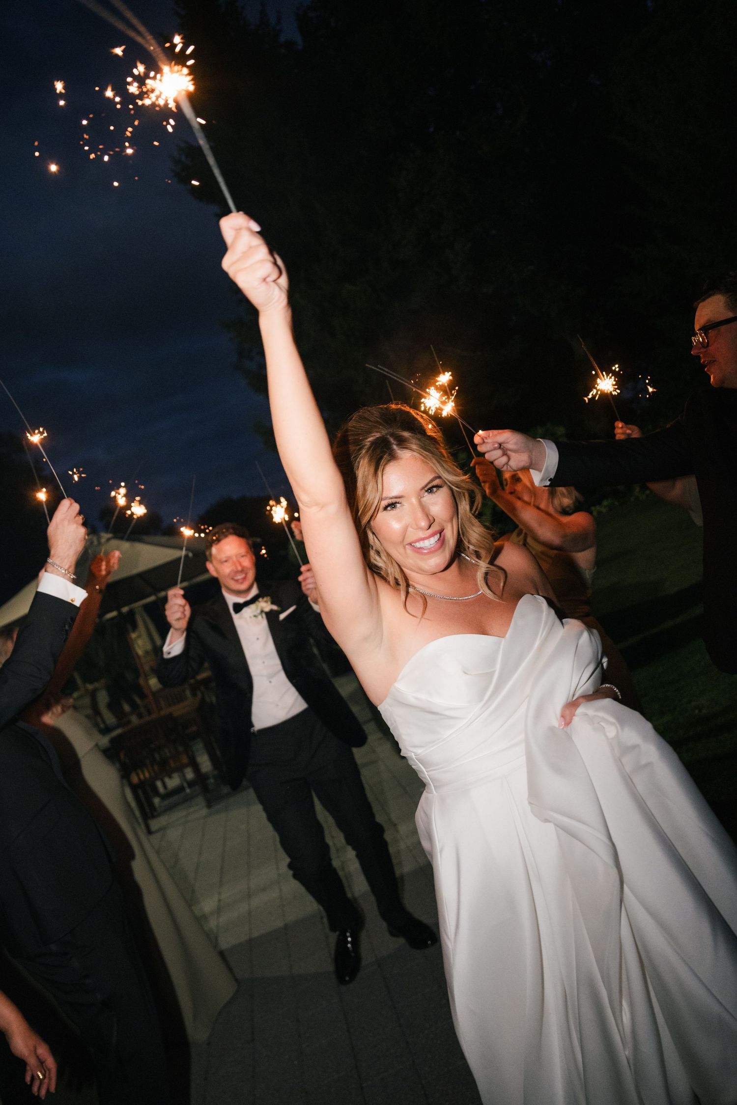 Wedding celebration at night with sparklers creating a magical atmosphere as guests dance and celebrate.