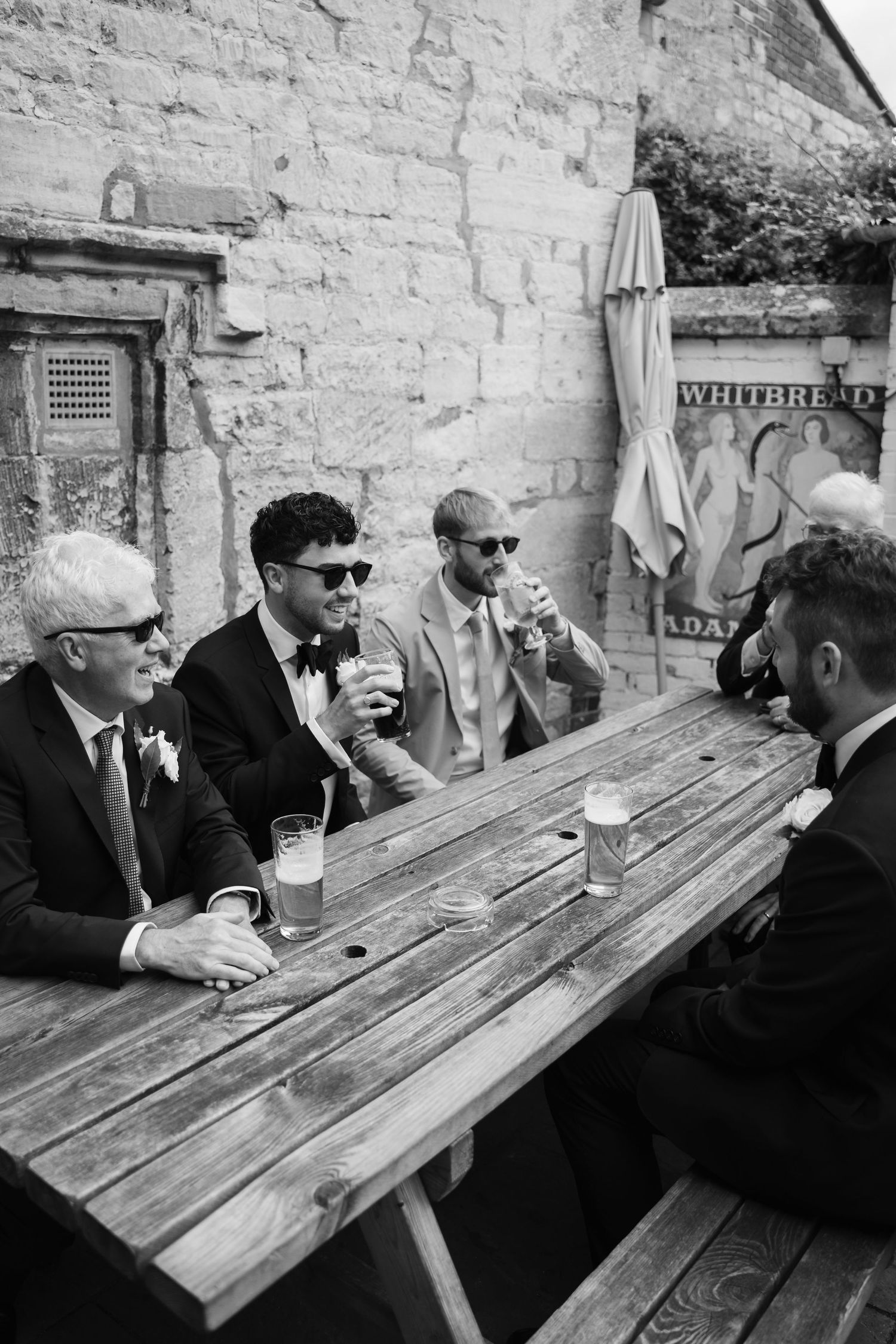 Black and white photo sequence of people sitting and conversing at outdoor wooden picnic tables.
