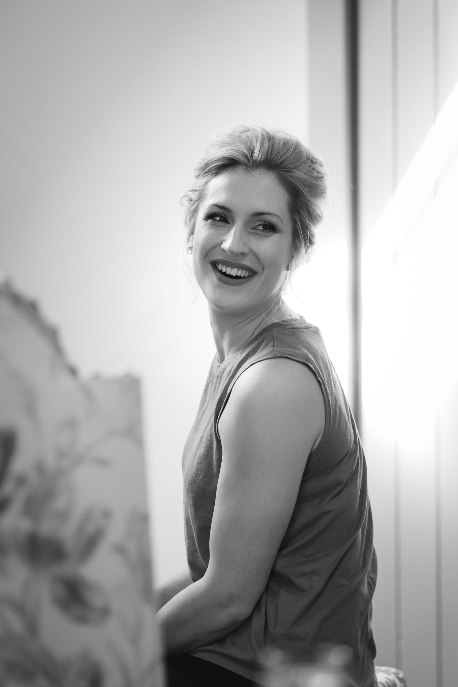 Black and white photo series showing a person in a sleeveless top laughing and posing against a bright window.