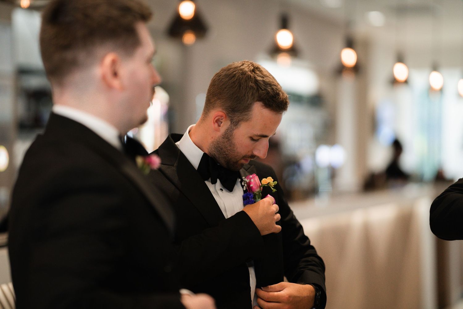 Emotional wedding ceremony moment with guests in black tie attire in a bright indoor venue.