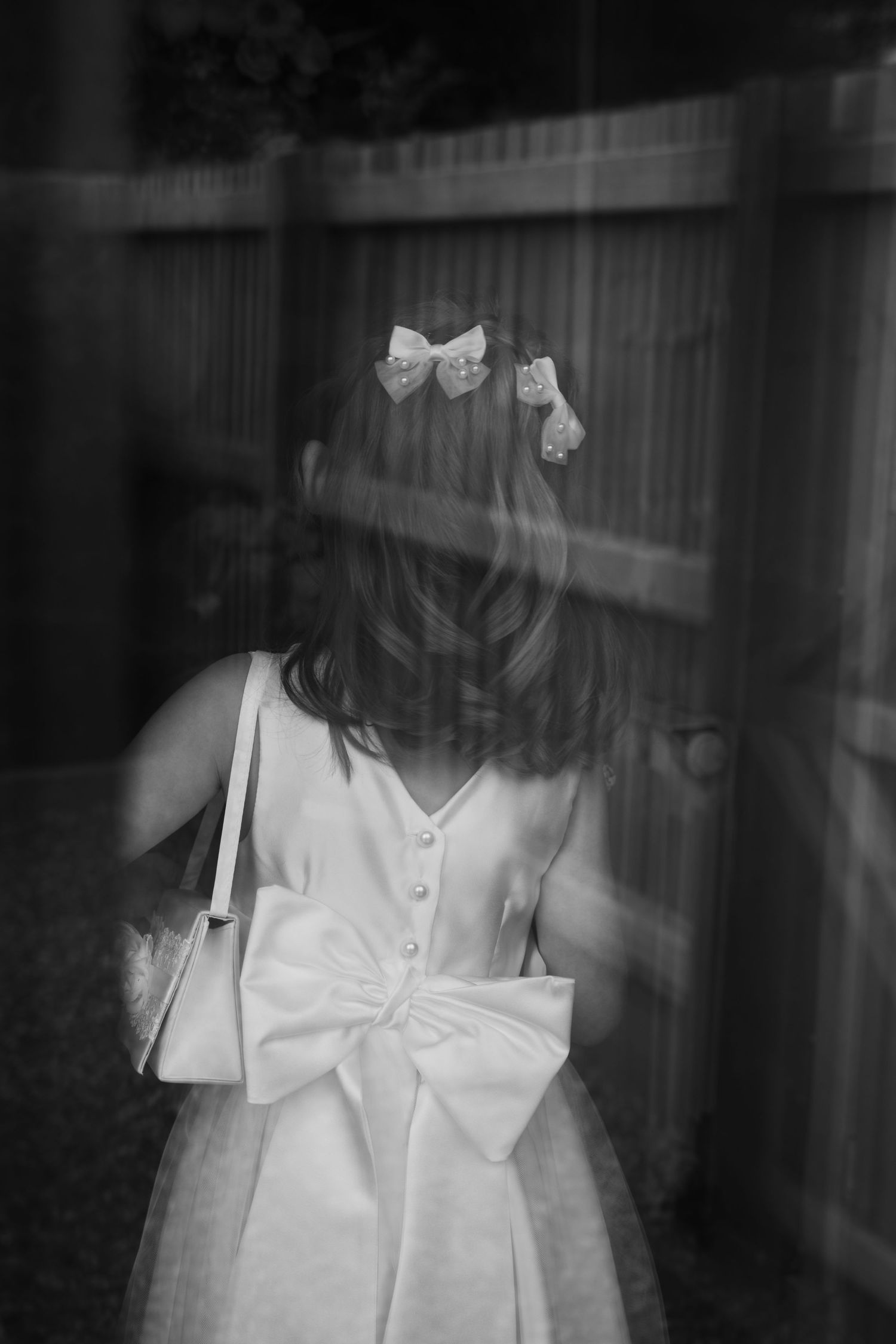Black and white artistic portrait showing a white dress with bow details and ethereal double exposure effect.