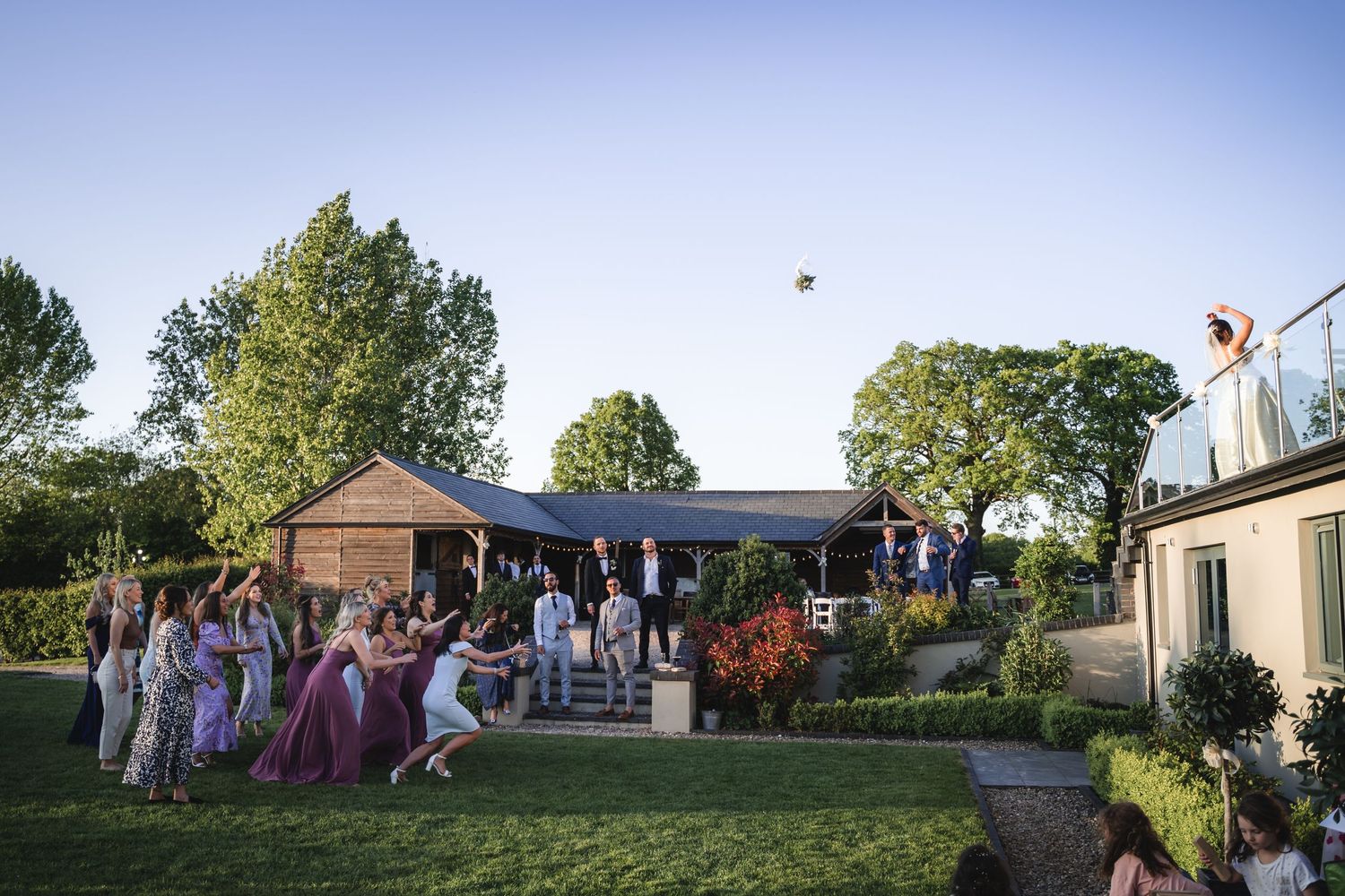 A panoramic view of an outdoor gathering at sunset with people enjoying festivities on a grassy lawn.