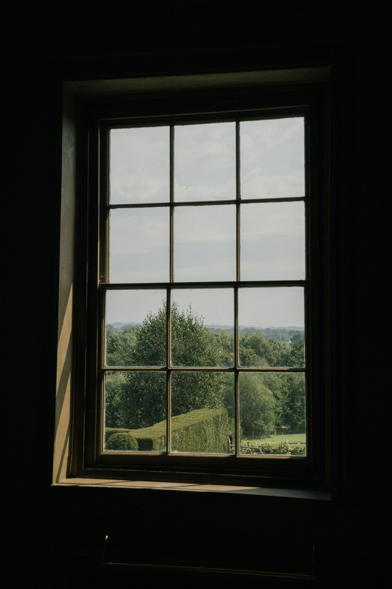 A series of windows looking out onto a green hillside landscape, showing progressively darker lighting conditions.