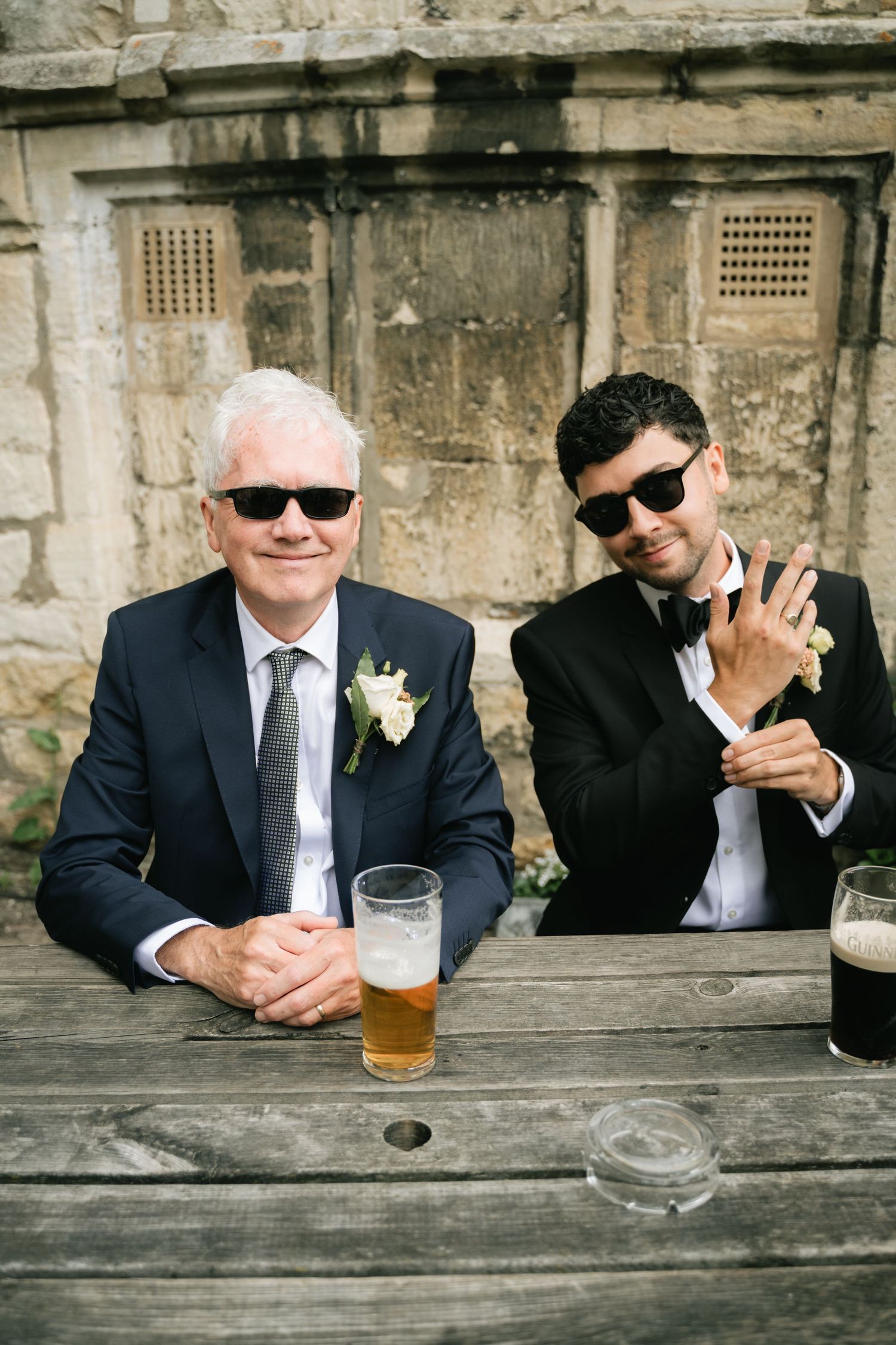 A series of candid photos showing groomsmen in suits and sunglasses relaxing with drinks at a rustic wooden bar.