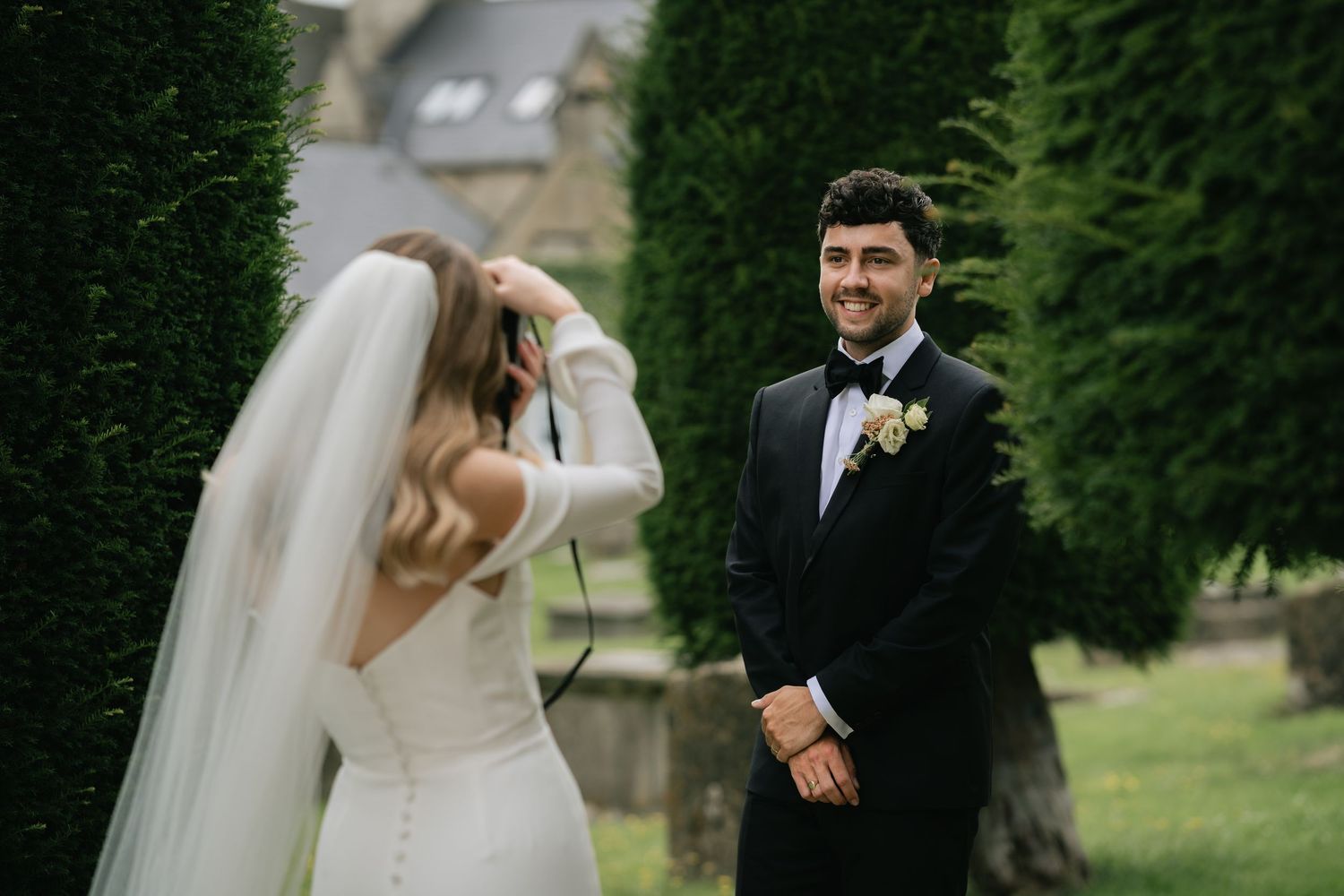 Newlywed couple shares intimate moments during outdoor wedding photoshoot in a lush green garden setting.
