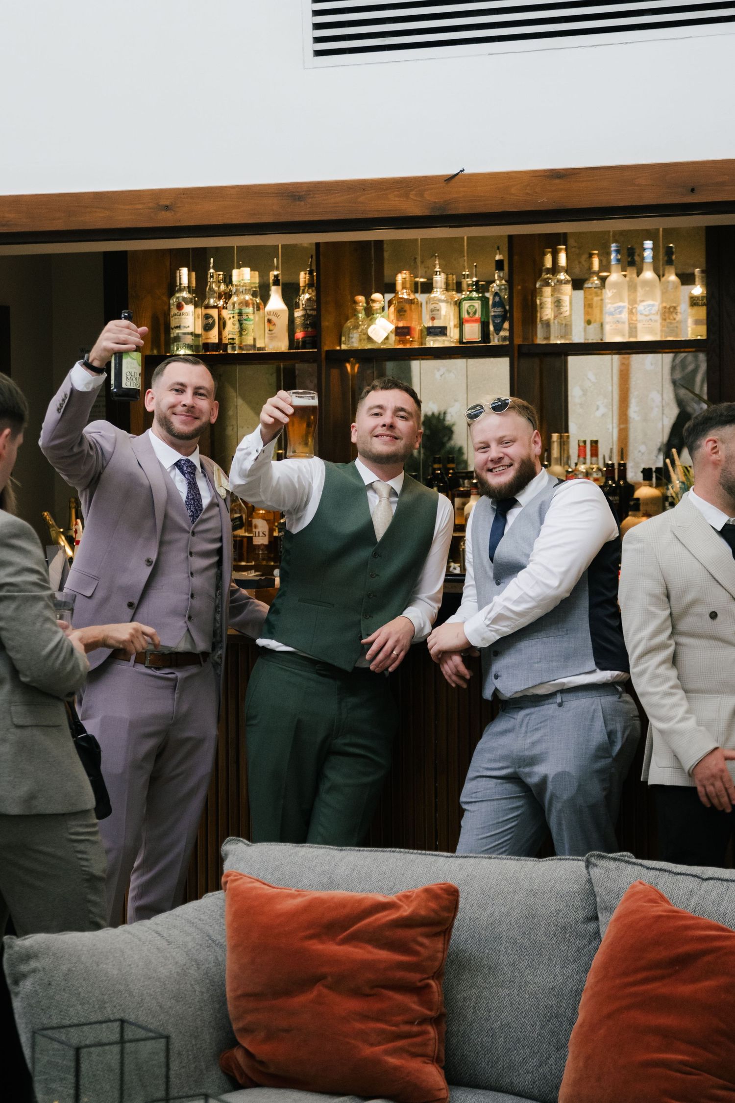 A sequence of candid moments showing wedding guests laughing and socializing at a reception bar area.