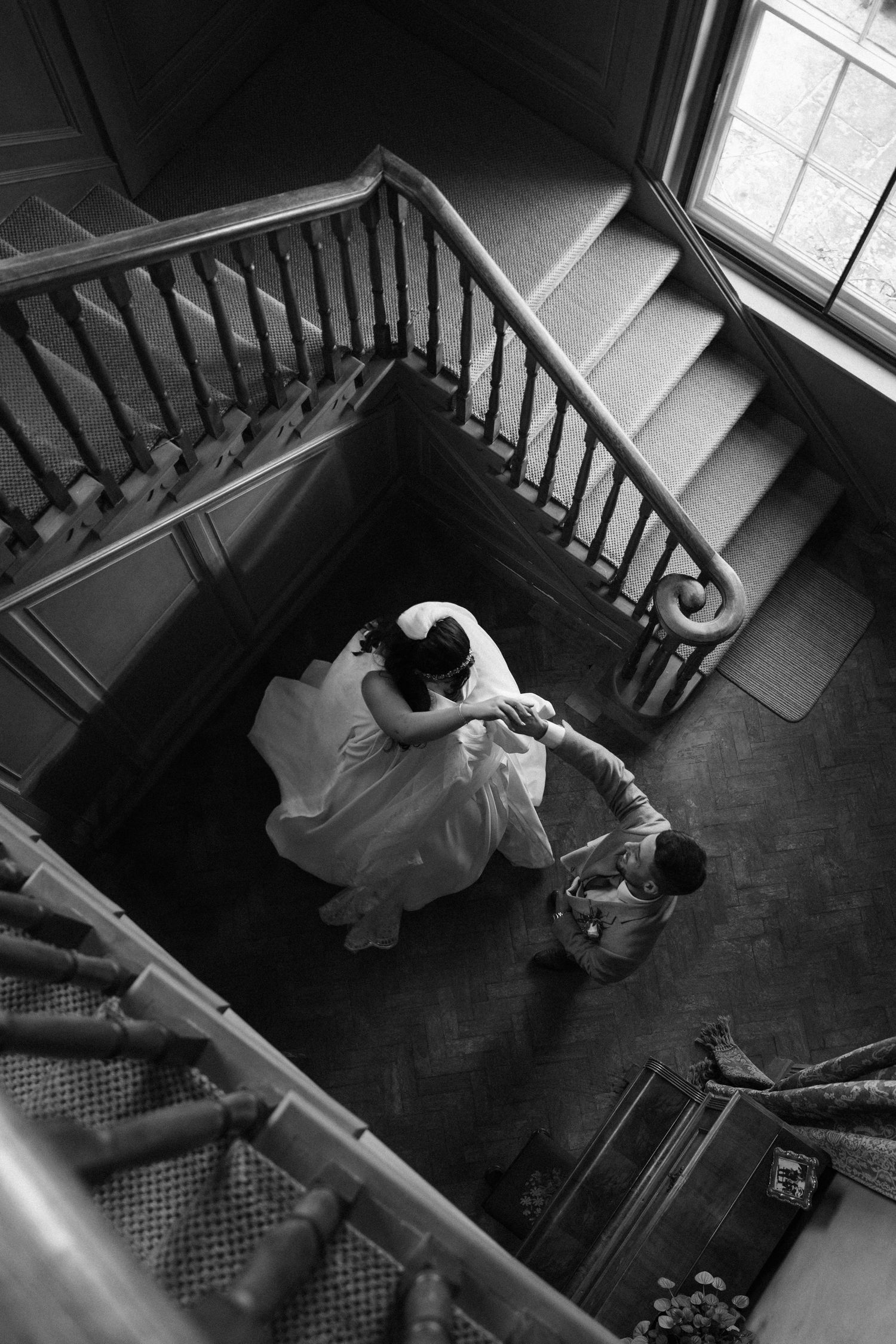 Black and white aerial view of a grand staircase with wedding party descending the steps.