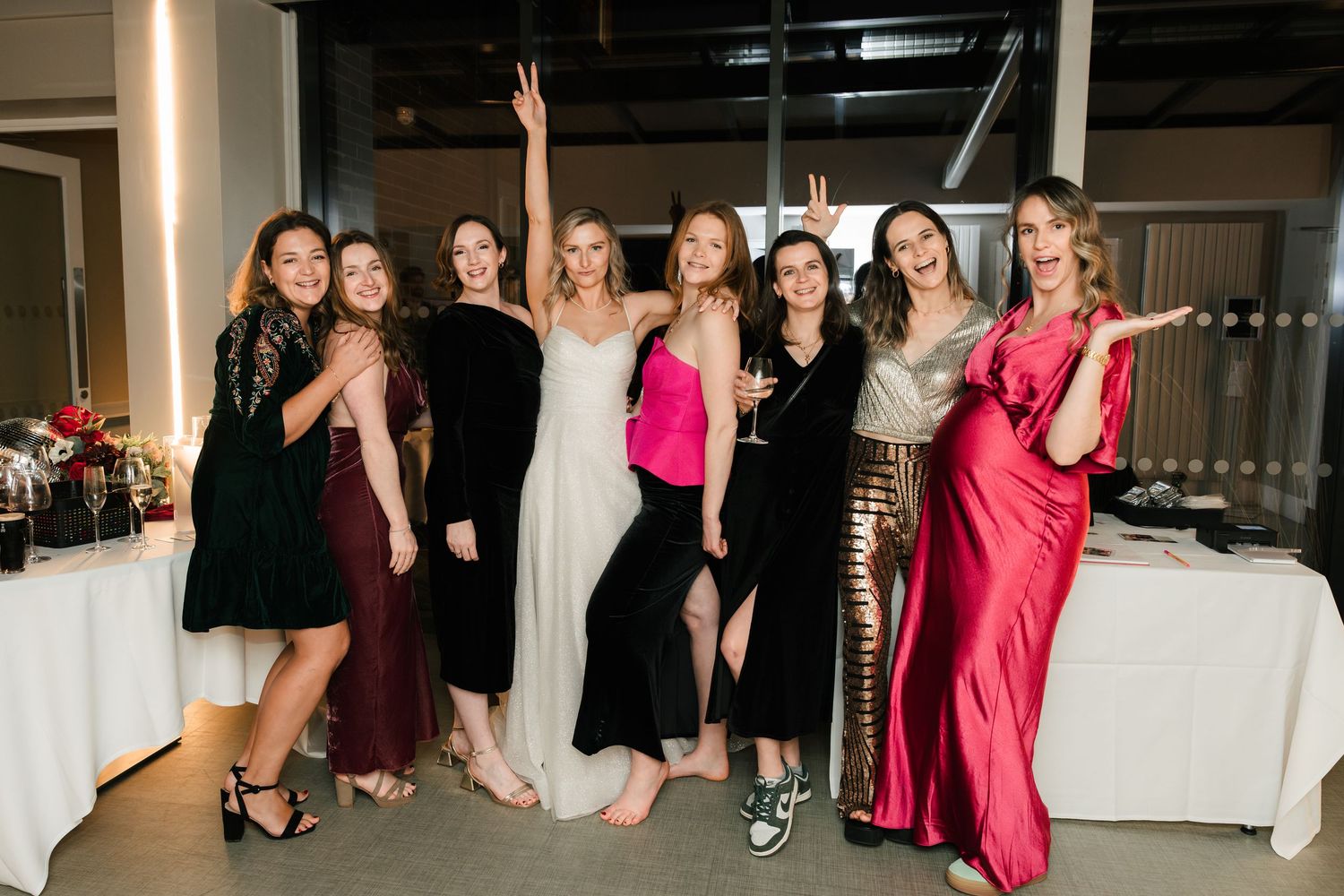 A group of people in formal attire pose and dance together at a festive celebration event.