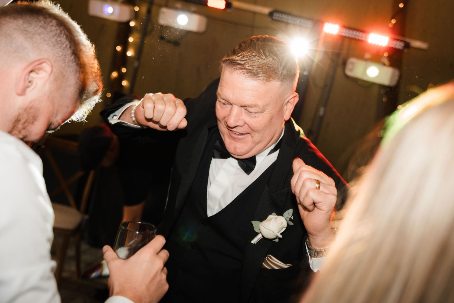 People dancing and celebrating at a formal event with dim lighting and festive atmosphere.