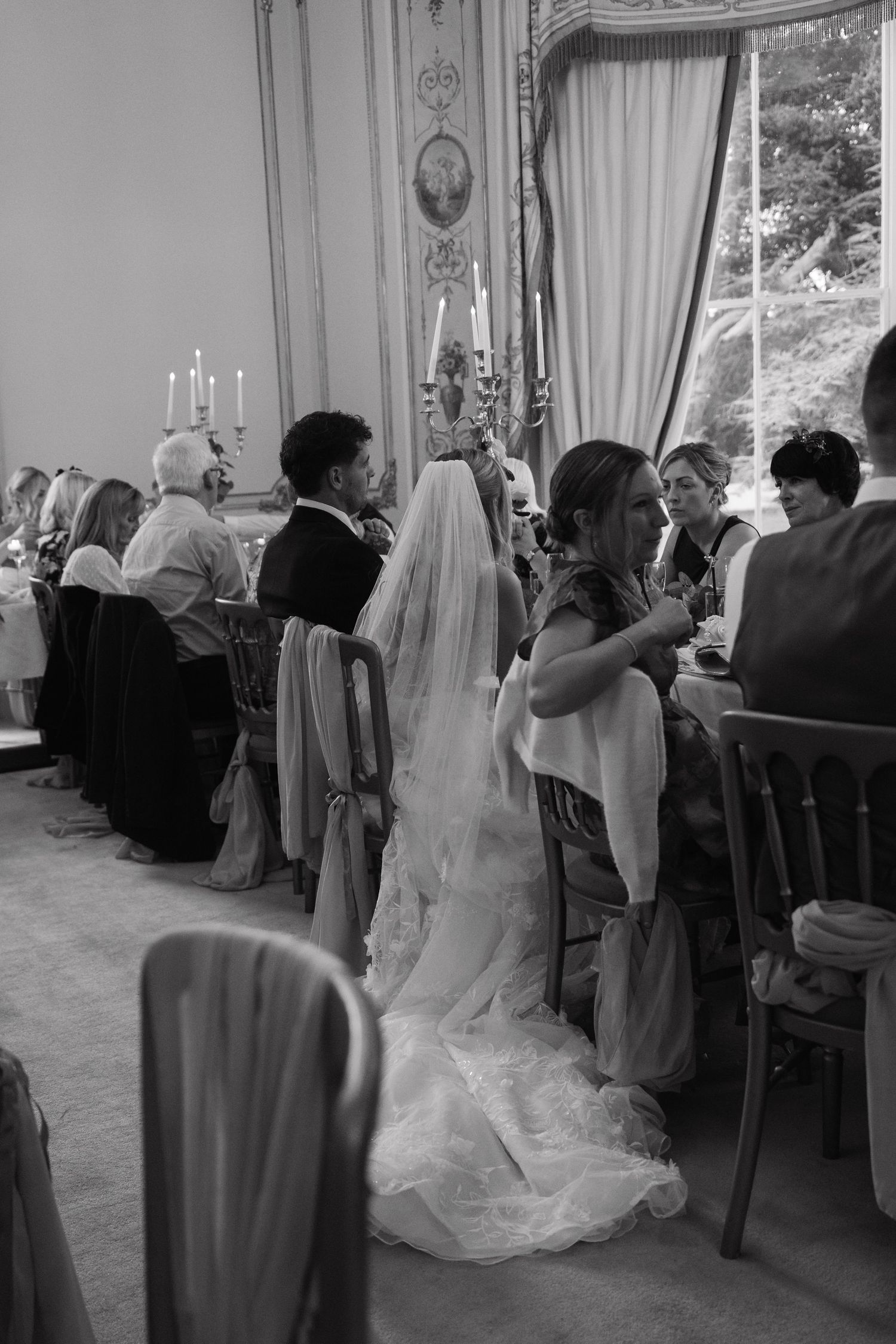 A sequence of black and white wedding reception photos showing guests mingling in an elegant ballroom setting.