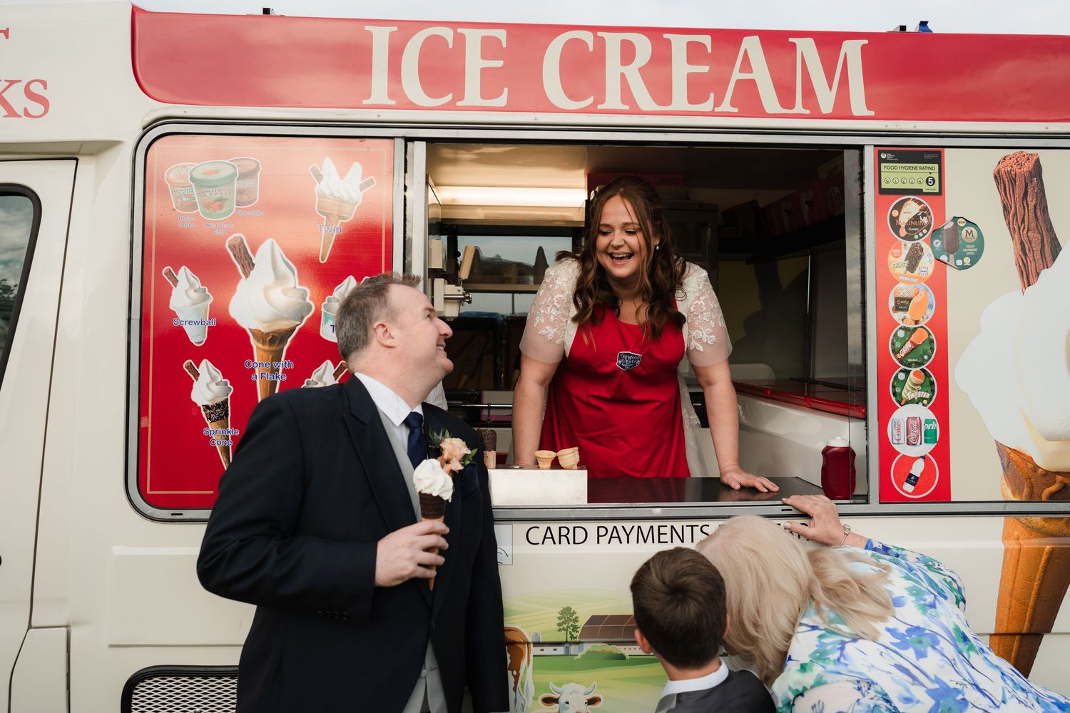 People gathered around an ice cream truck at an outdoor event with a festive atmosphere.