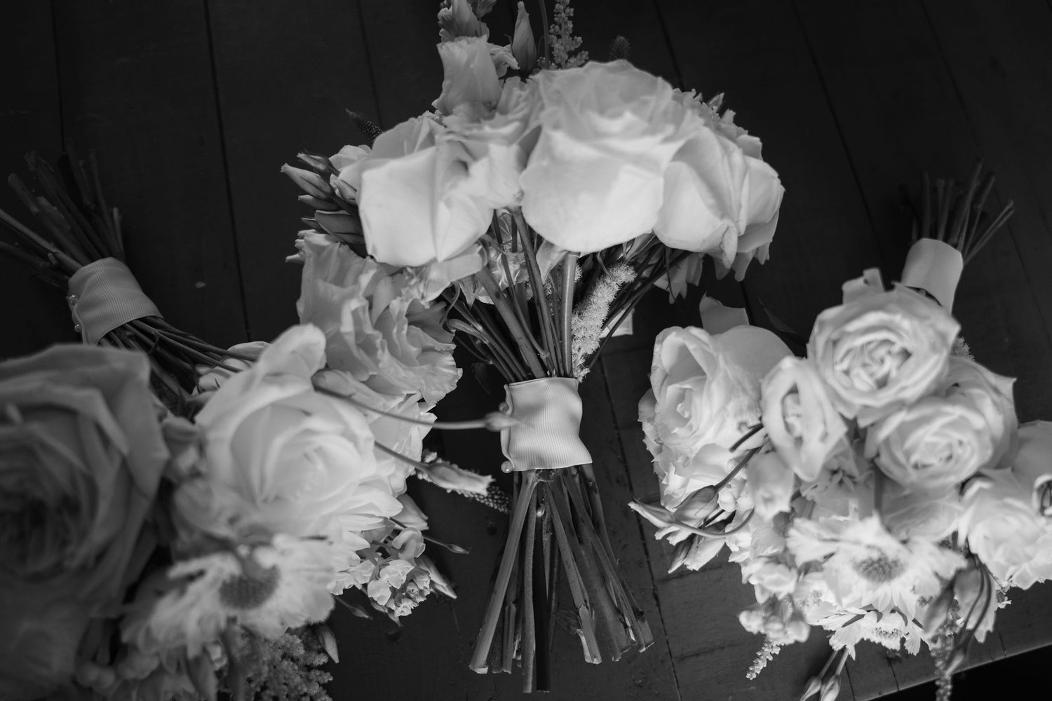 Elegant white rose bouquets arranged with ribbons in monochrome style.