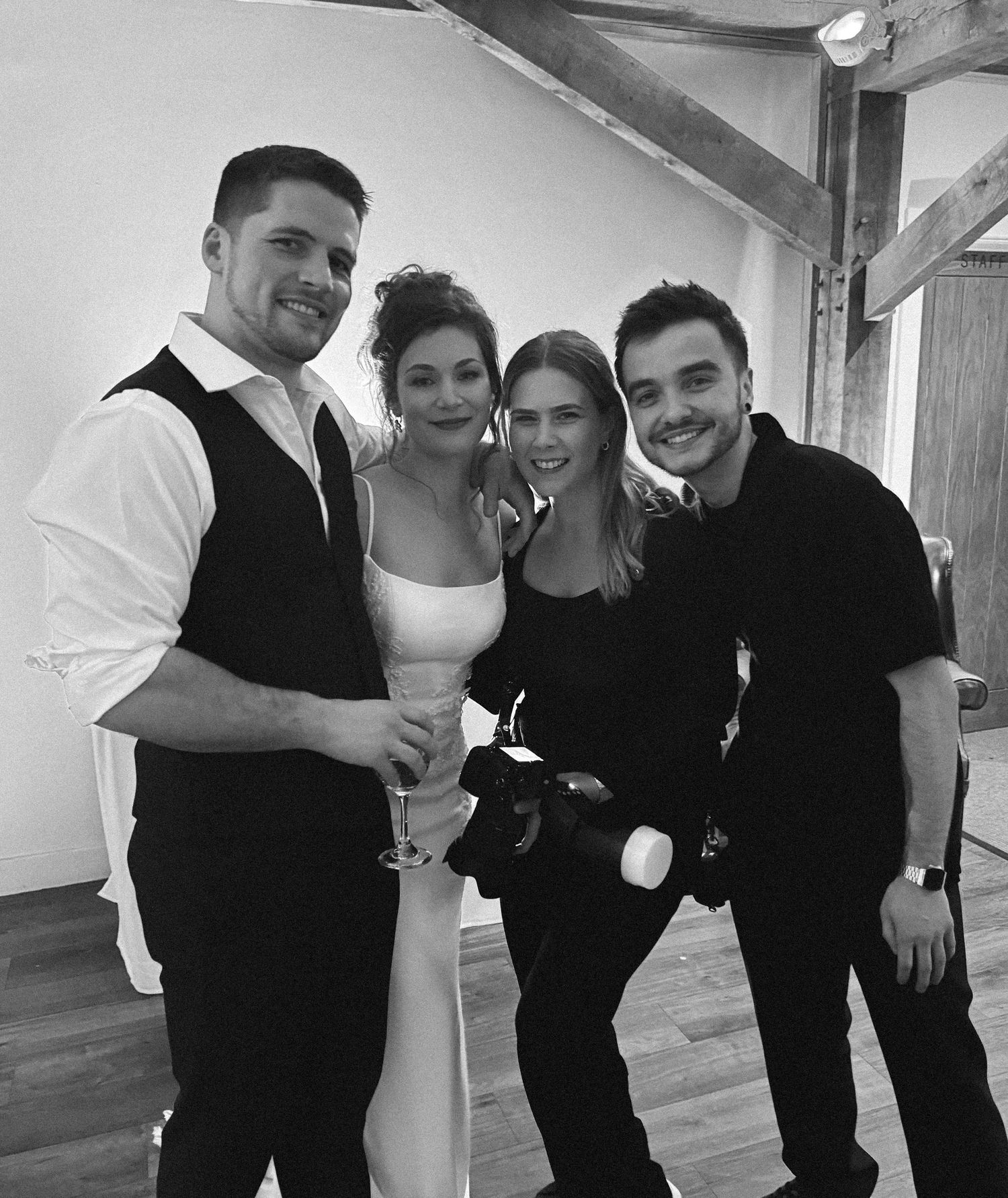 A group of people dressed in black and white outfits pose together in a casual indoor setting.