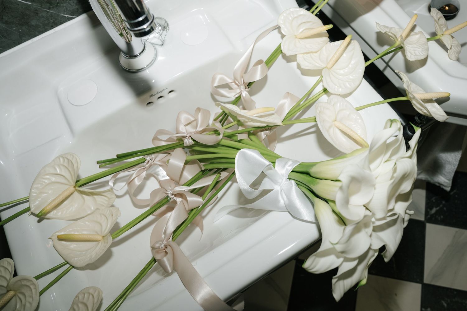 White calla lilies and butterfly decorations arranged on a checkered surface with a white tablecloth.