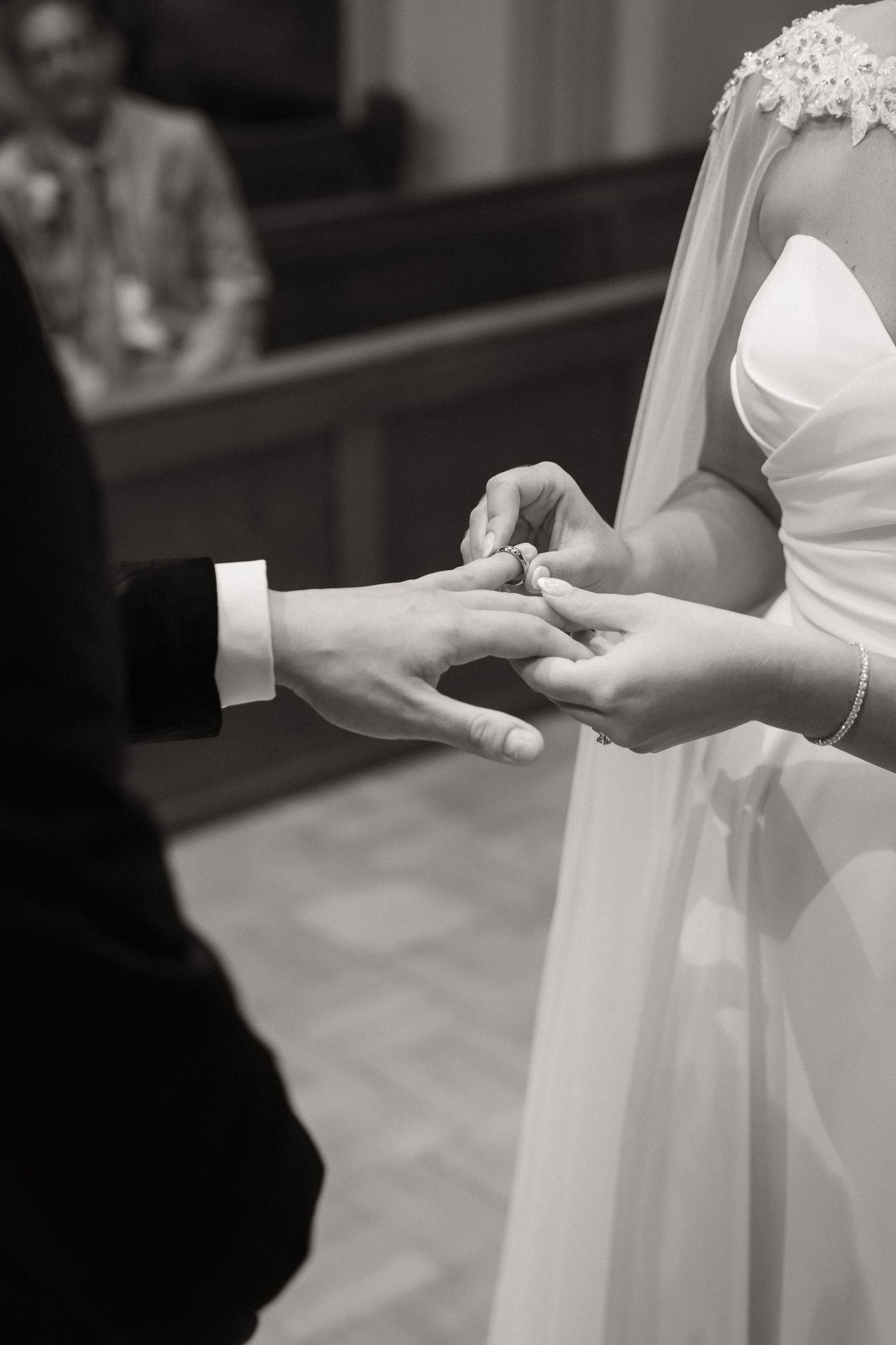 Close-up shots of wedding ring exchange ceremony showing hands and white dress details.